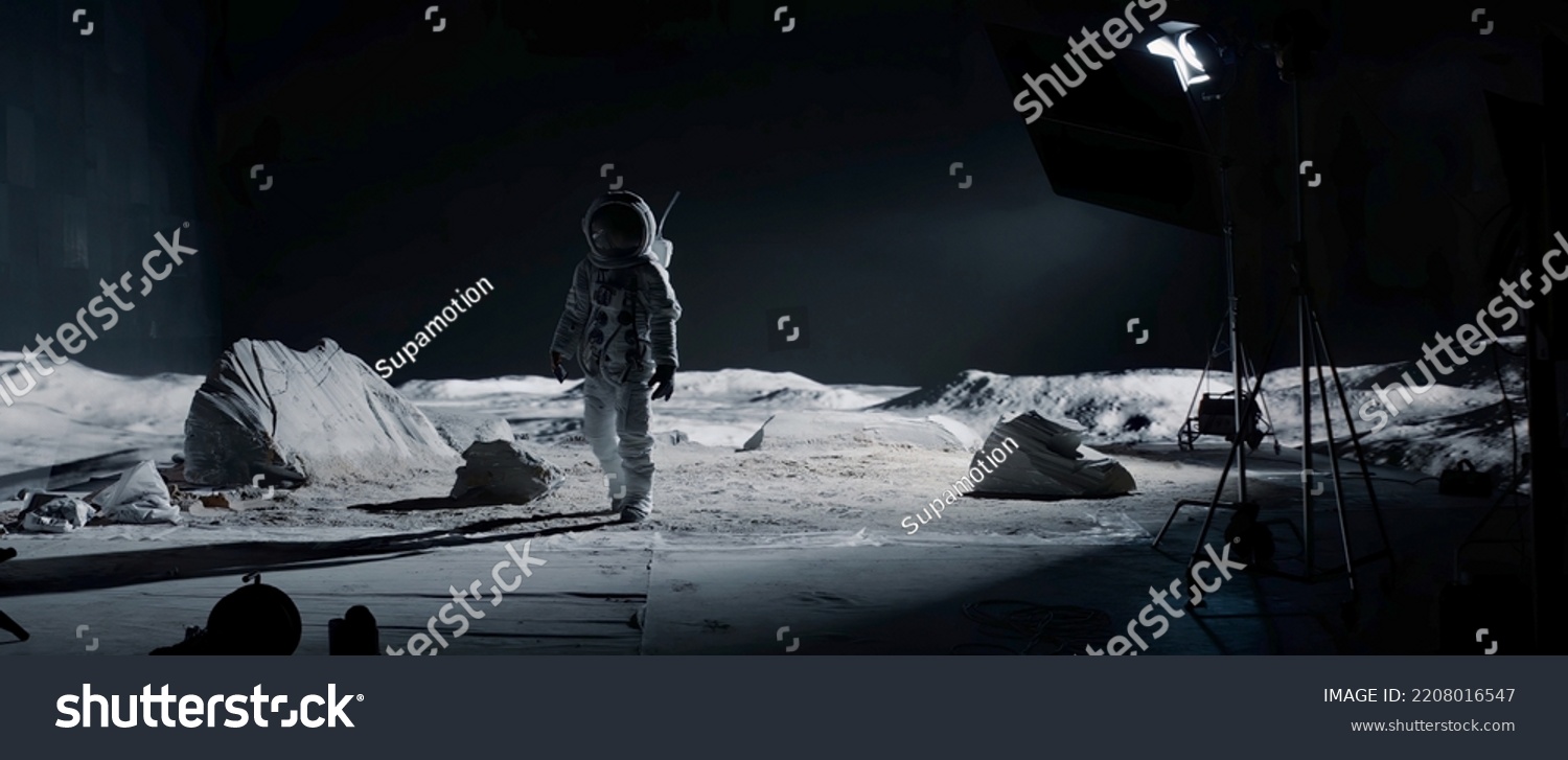 WIDE Behind the scenes - male actor in astronaut waking towards the camera on on a Moon Lunar movie shooting set #2208016547
