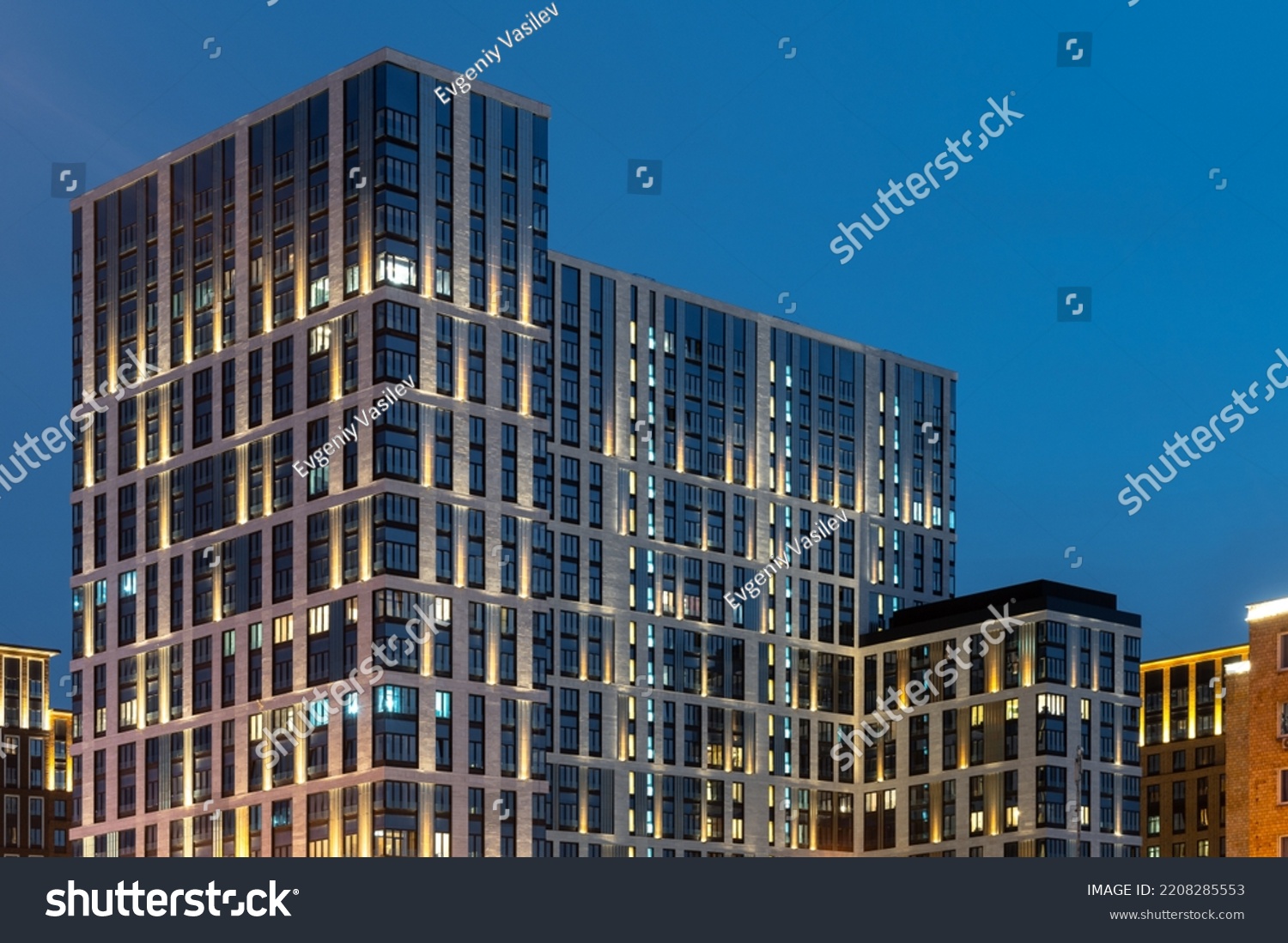 The facade of a residential building in the evening with street lighting . Modern architecture . Night City.  #2208285553