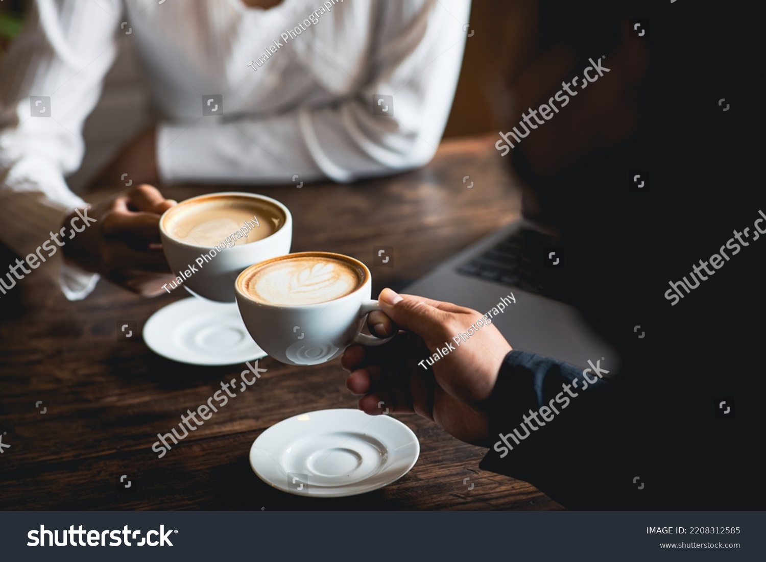 Close-up of a man and woman clinking a white coffee cup in a coffee shop. while talking at work #2208312585