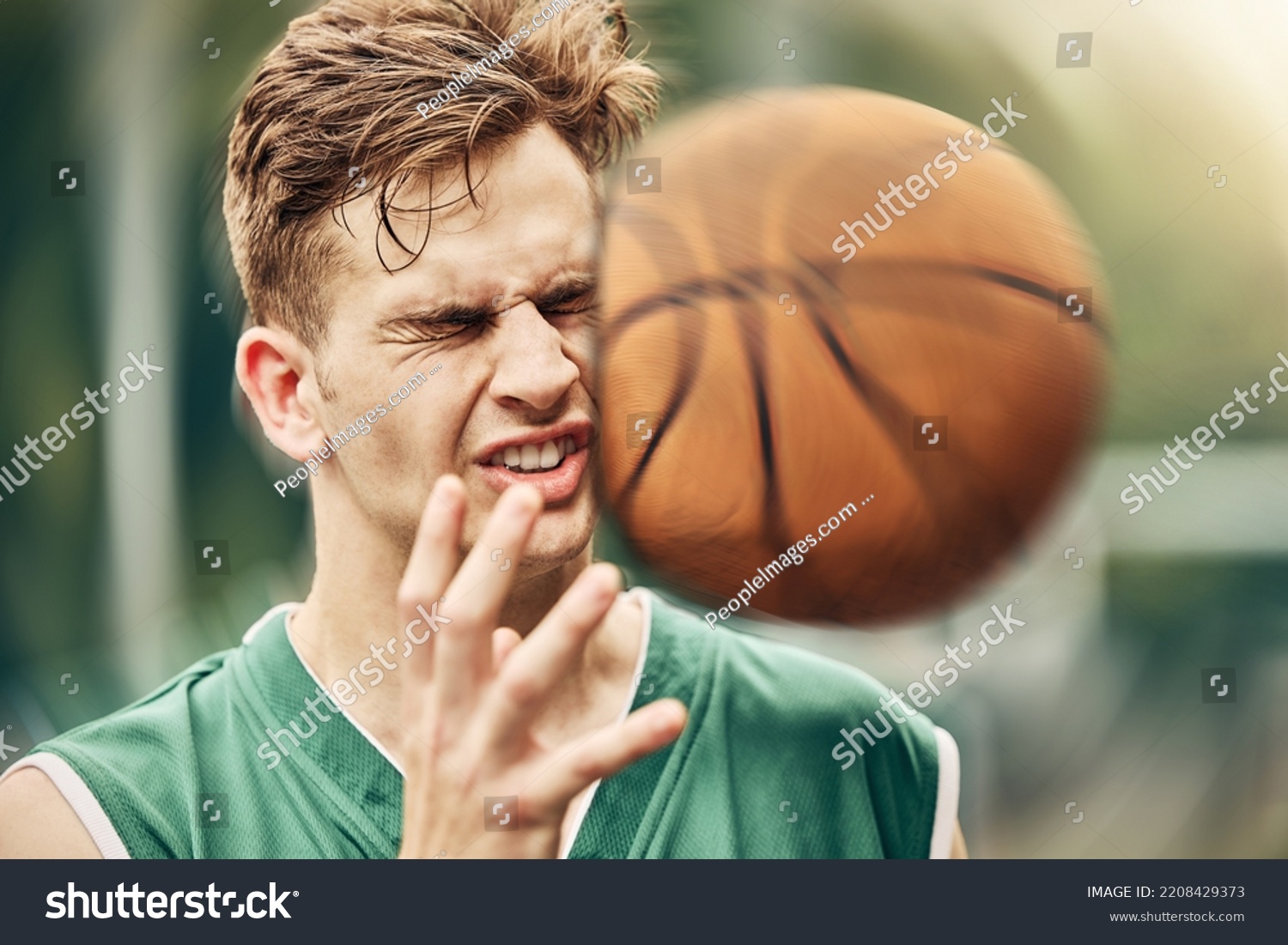 Sports, basketball and accident with face in game match on athlete court for tournament training. Injured man in professional outdoor fitness centre in pain from impact of ball hit action. #2208429373