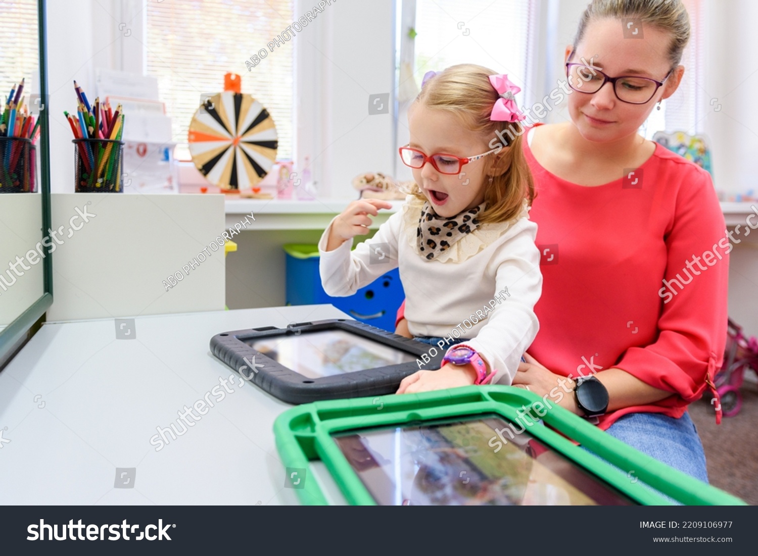 Non-verbal girl living with cerebral palsy, learning to use digital tablet device to communicate. People who have difficulty developing language or using speech use speech-generating devices. #2209106977