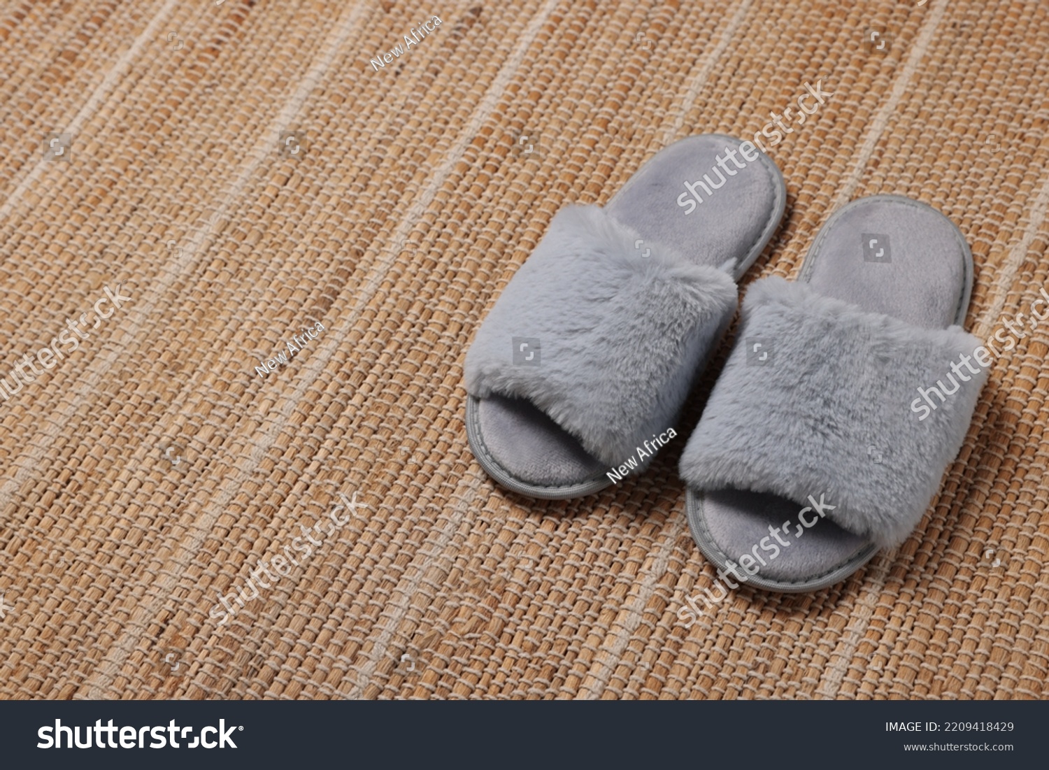 Soft fluffy grey slippers on carpet, space for text #2209418429
