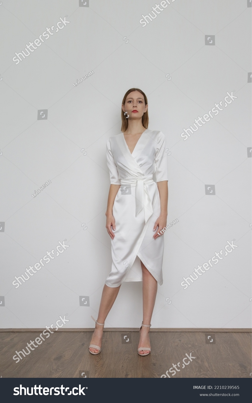 Serie of studio photos of attractive young woman wearing elegant white silk satin dress.	 #2210239565