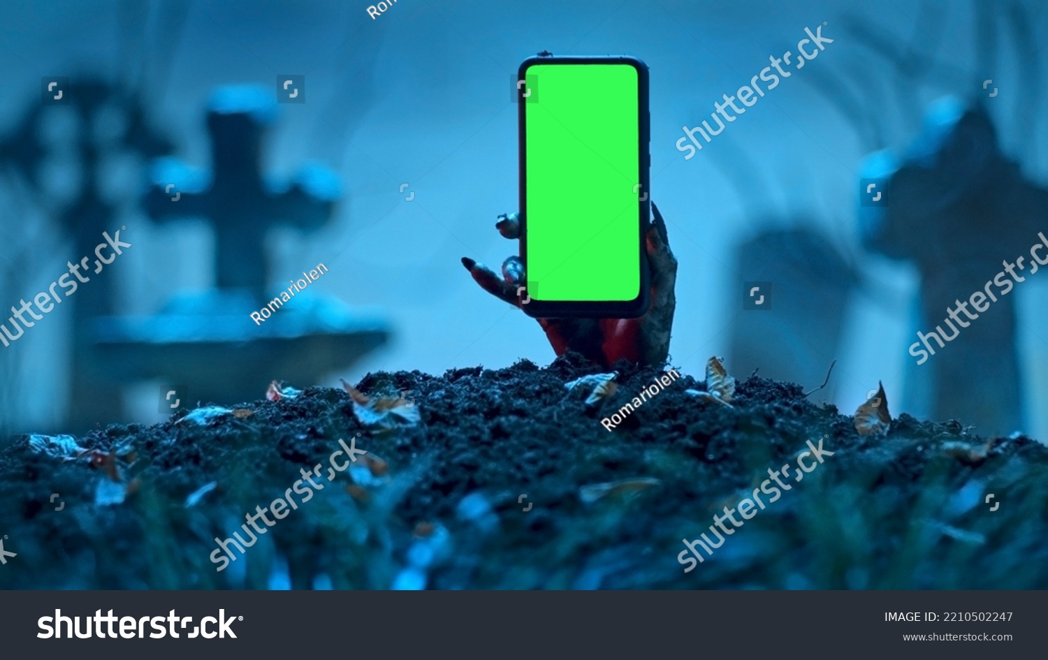 Zombie hand rising up smartphone with green screen out of grave. Holiday event halloween concept. #2210502247