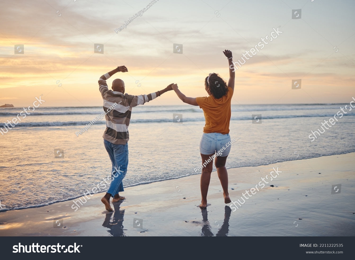 Love, travel and happy couple at beach enjoying summer vacation or fun honeymoon at sunset while holding hands and being playful. Laughing, energy and seaside holiday with black man and woman at sea #2211222535