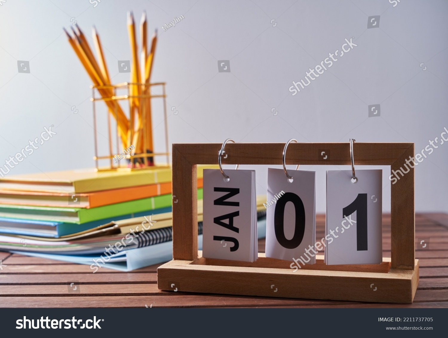 Calendar 1st january with stack of book and penin pencil holder against white wall #2211737705