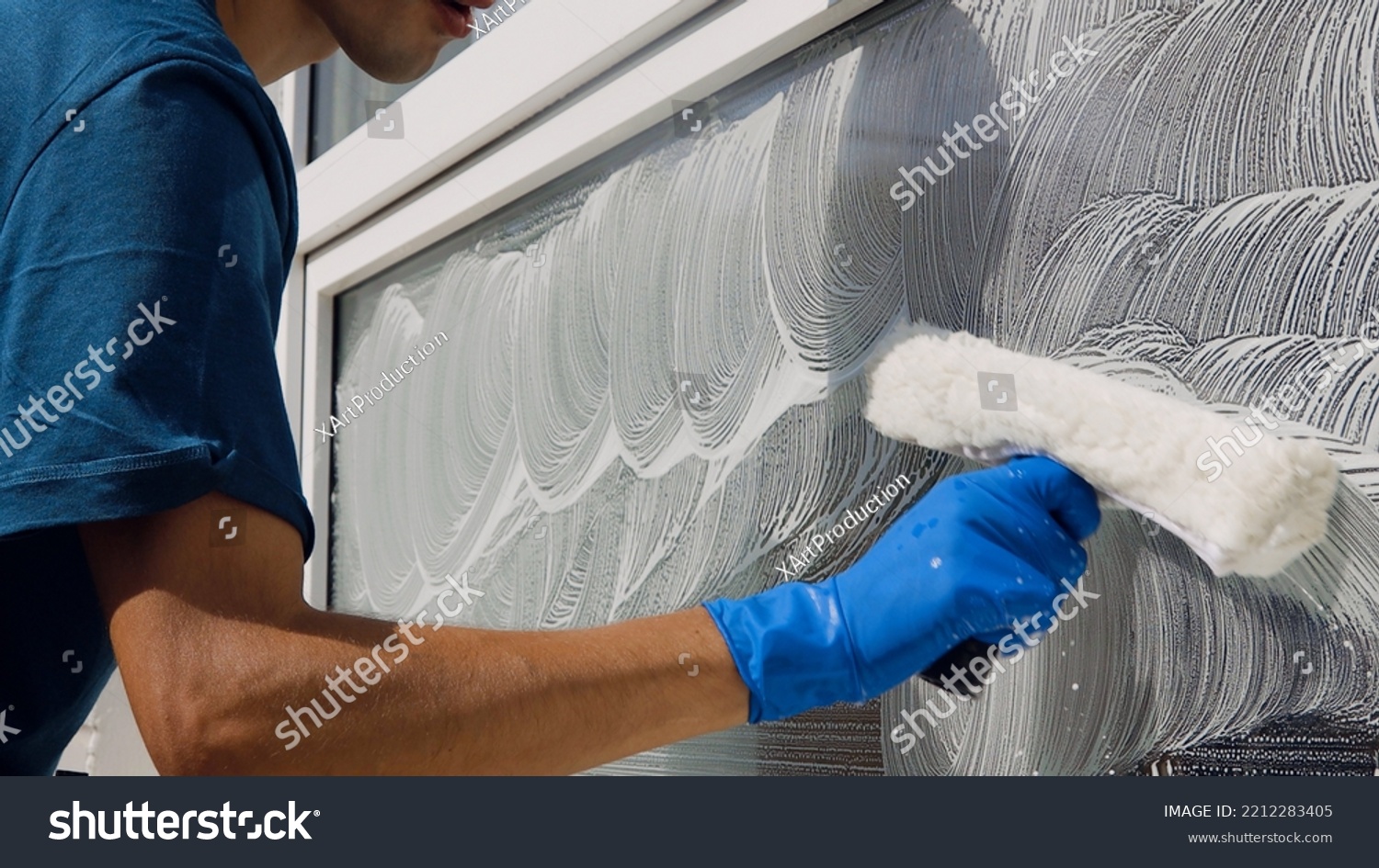 Male professional cleaning service worker in overalls cleans the windows and shop windows of a store with special equipment #2212283405