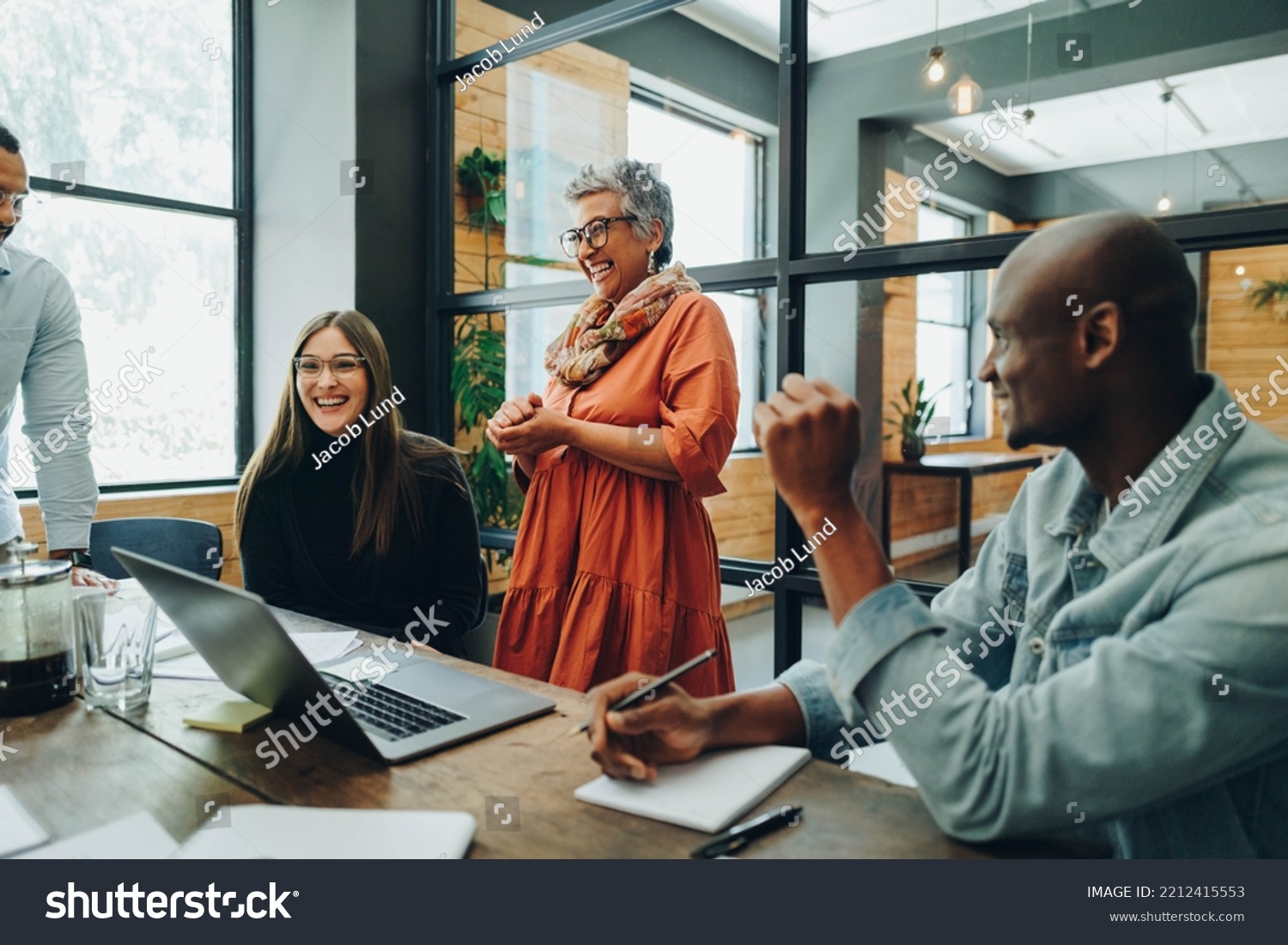 Diverse businesspeople smiling cheerfully during a meeting in a modern office. Group of successful businesspeople working as a team in a multicultural workplace. #2212415553