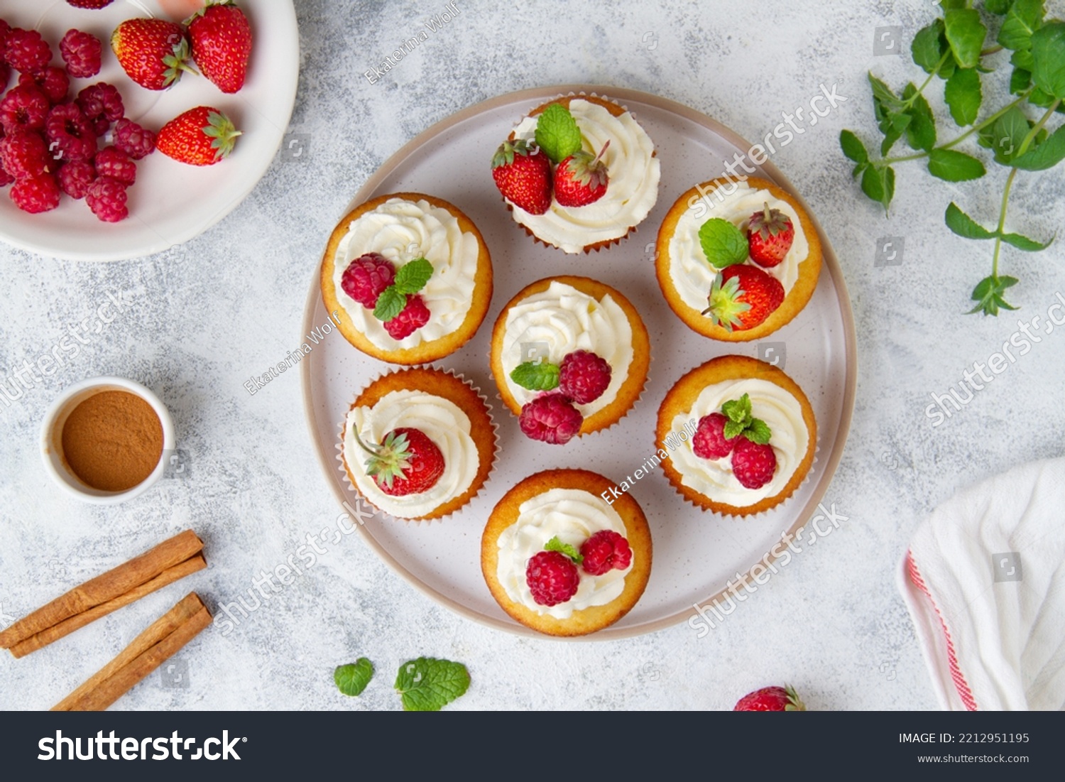Cupcakes with raspberries and strawberries on a plate on a concrete background, top view #2212951195