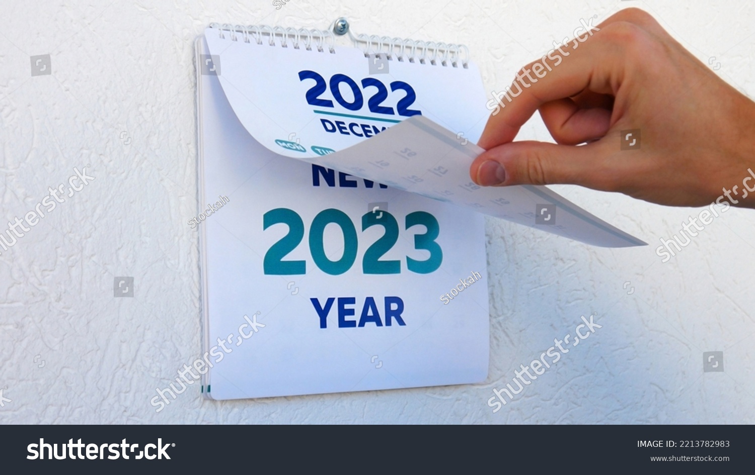 Close-up of male hands flipping through the December page of 2022 wall calendar followed by the title page of a new 2023 calendar #2213782983
