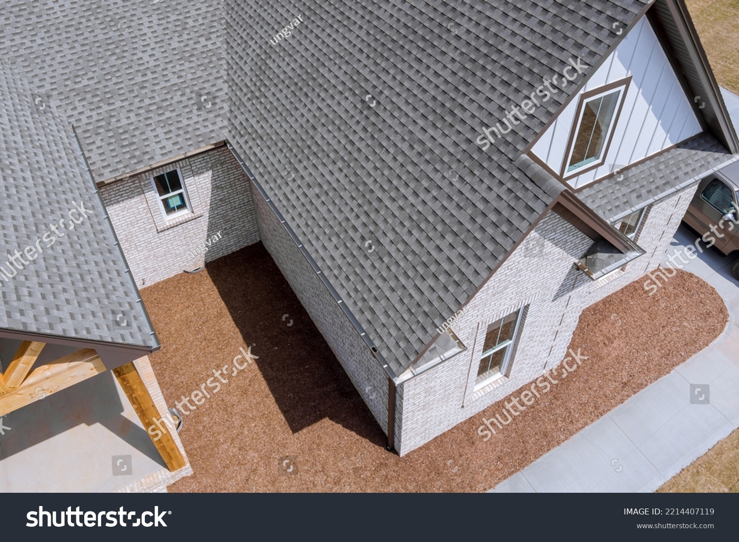 Roof of newly built house is being covered with asphalt shingles during construction while house is still being built #2214407119