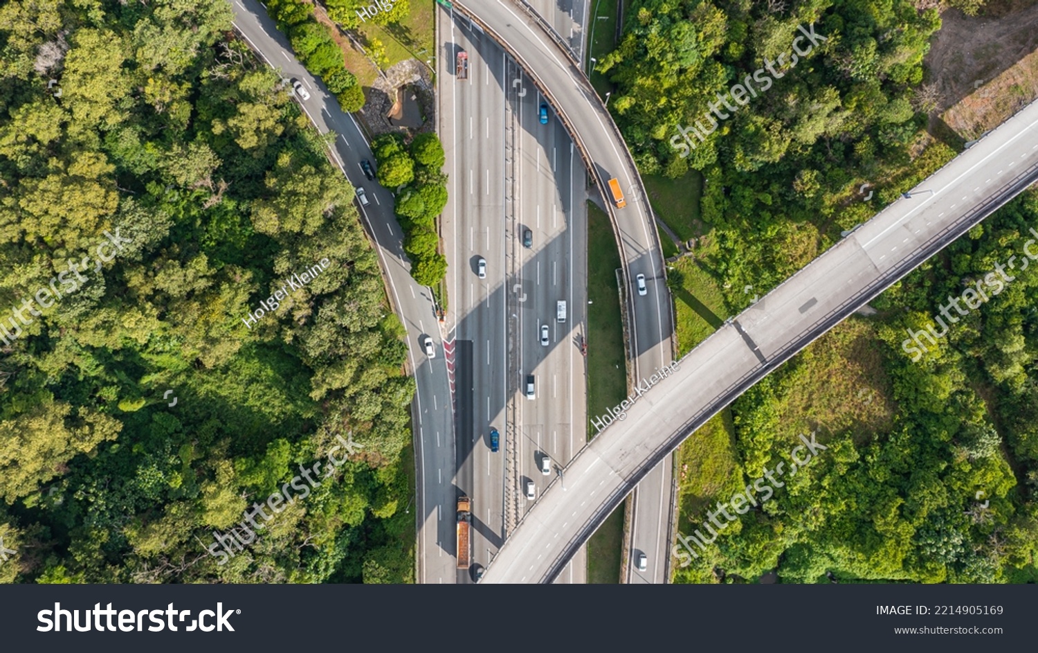 Aerial view directly above a six lane highway. Top view of asphalt road passes through the field and forest. Aerial. Sedan cars driving by the highway. Top view from drone. aerial photo autobahn road #2214905169