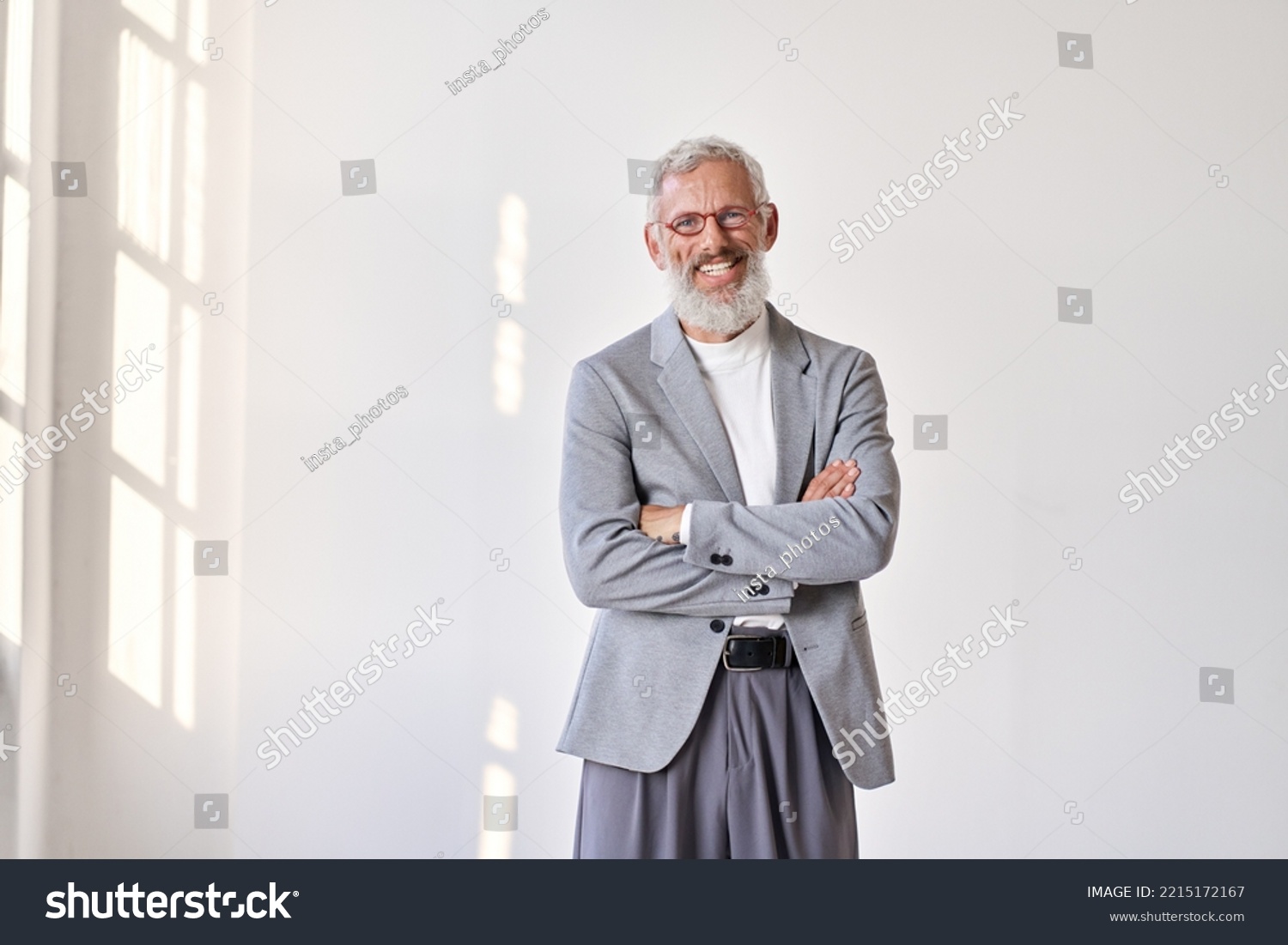 Happy mature older gray-haired business man leader, smiling middle aged old senior professional businessman teacher wearing suit and glasses standing arms crossed isolated on white wall. #2215172167