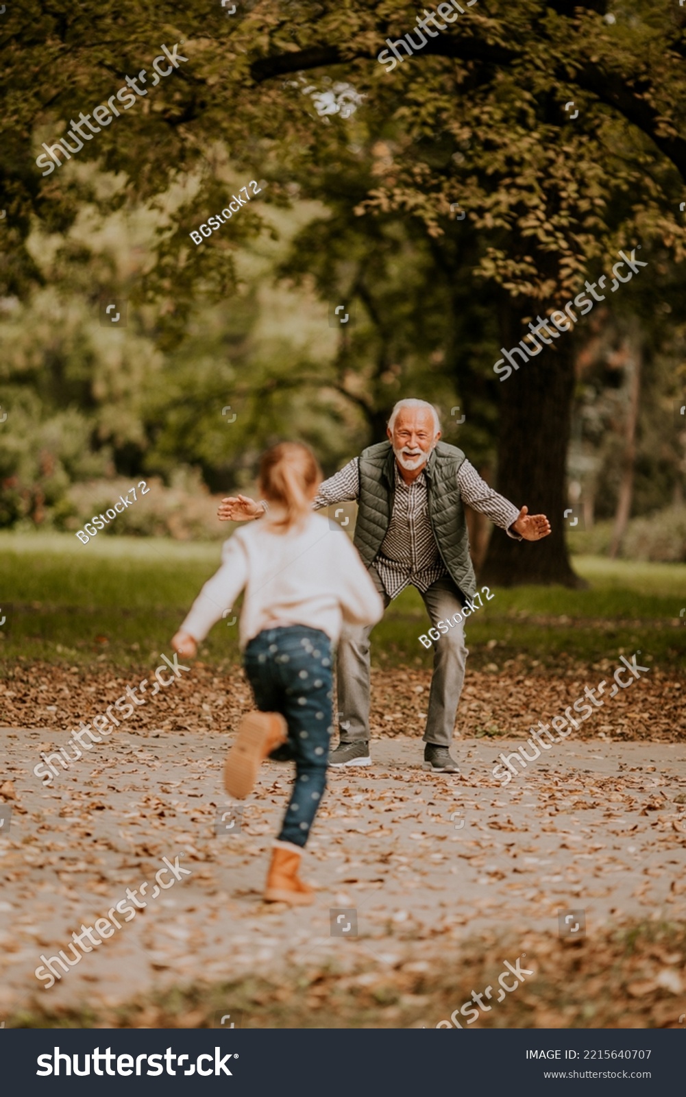 Handsome grandfather spending time with his granddaughter in park on autumn day #2215640707