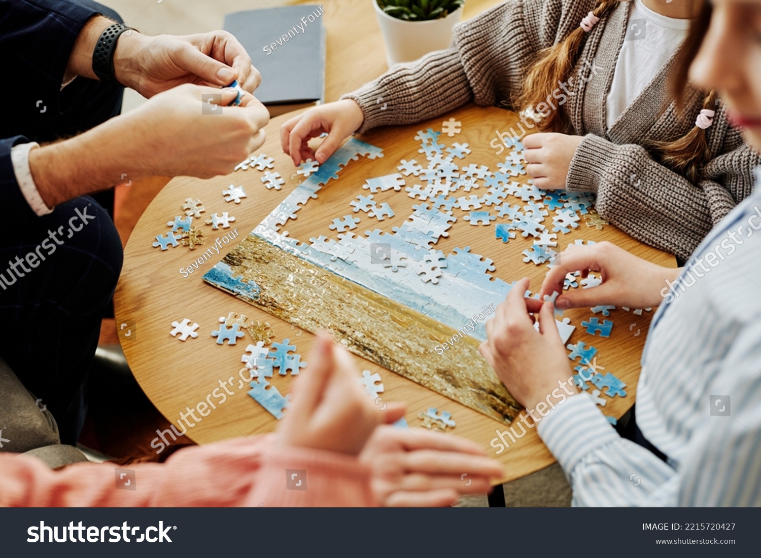 Close up of unrecognizable family playing jigsaw puzzle game together at home #2215720427