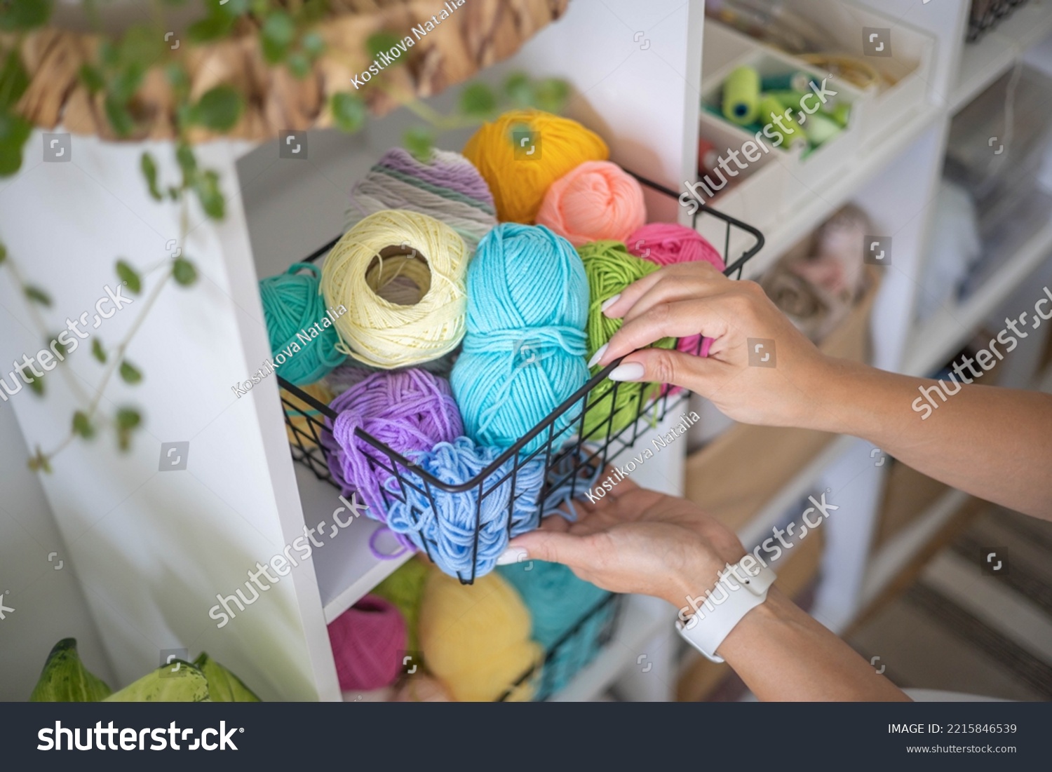 Female hands placing basket with colored ball of yarn for art crochet knitting ribbon cotton wool thread for hobby. Woman tailor sewing materials comfortable storage cupboard arrangement organize #2215846539