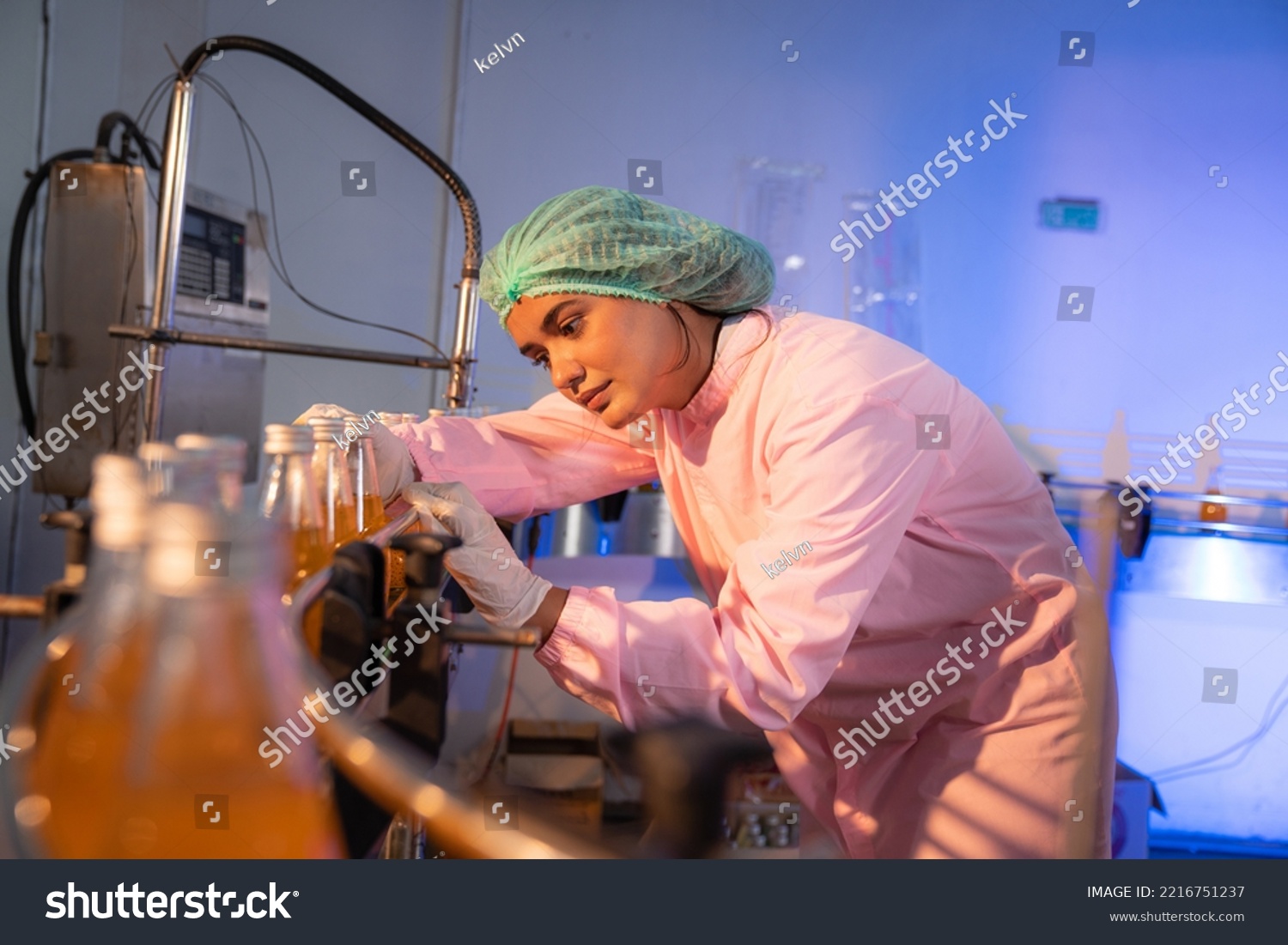 Woman Quality Control a fruit drink factory in glass bottles Inspecting glass bottle packaging for fruit juice drinks, Worker QC working in a drink water factory. #2216751237