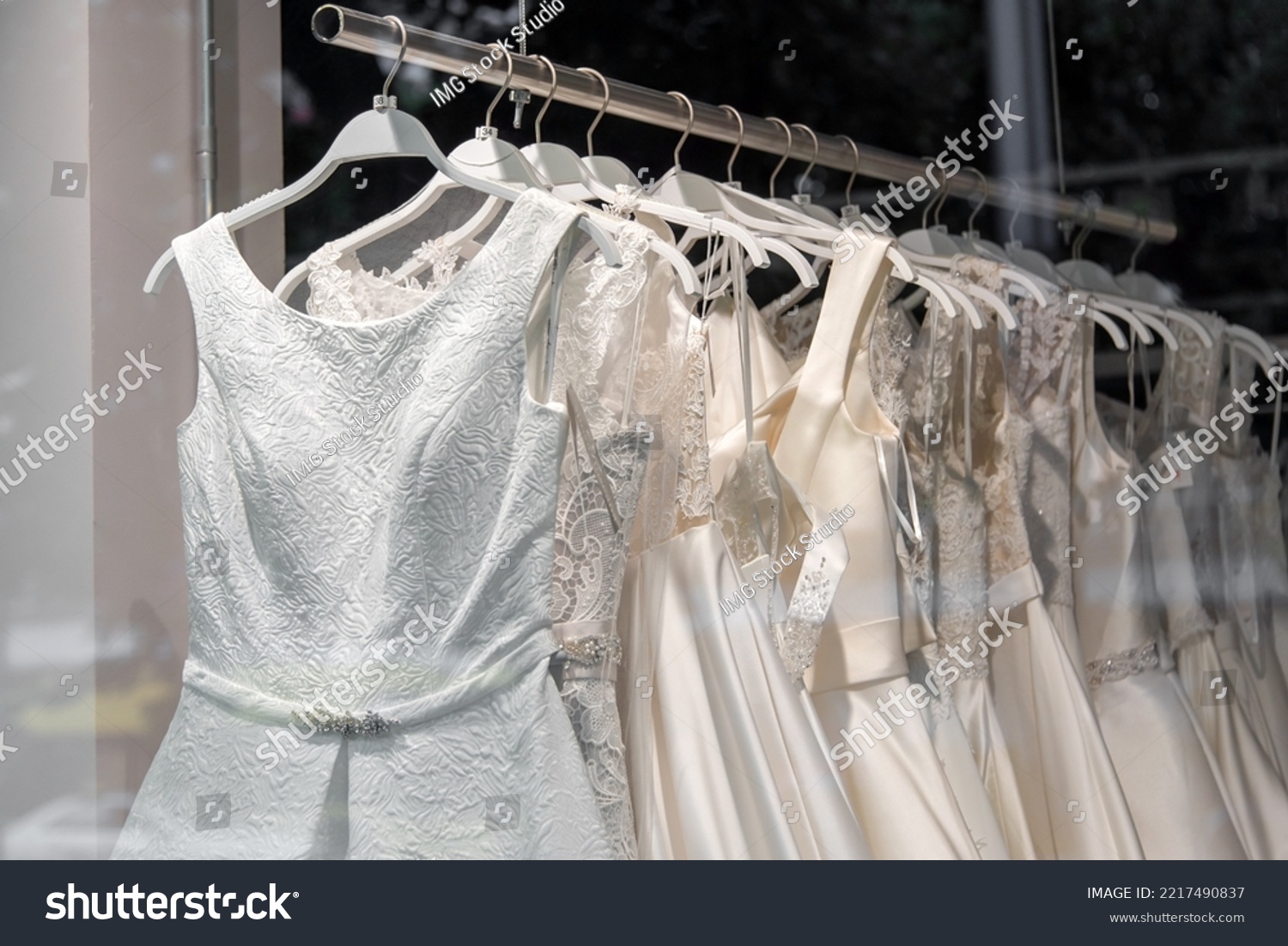 Beautiful bridal dress on hangers. Wedding dress close up at the wedding salon. Wedding dresses hanging on a hanger. Interior of bridal salon. #2217490837