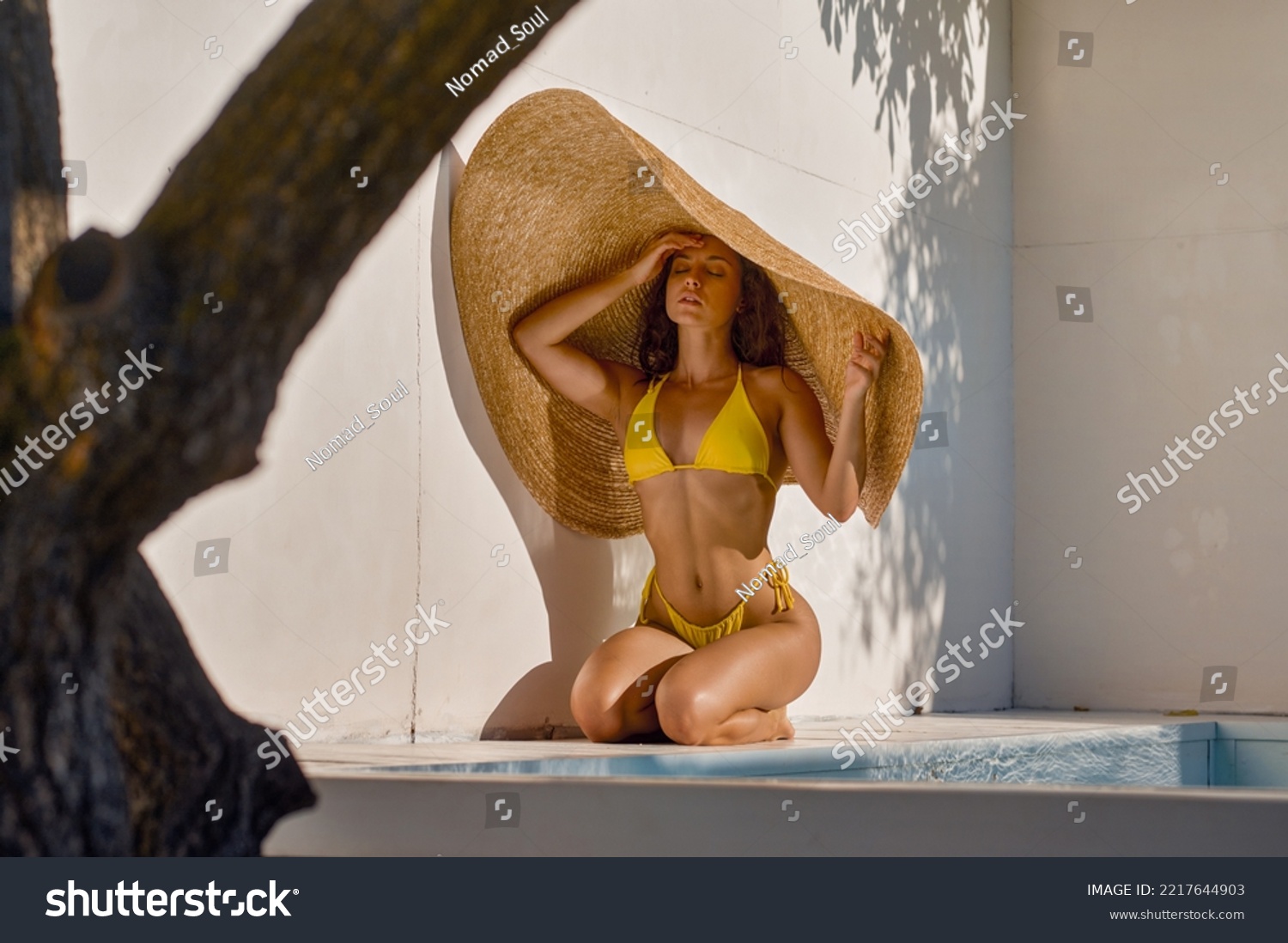 Attractive woman hiding from hot sun under big straw hat #2217644903