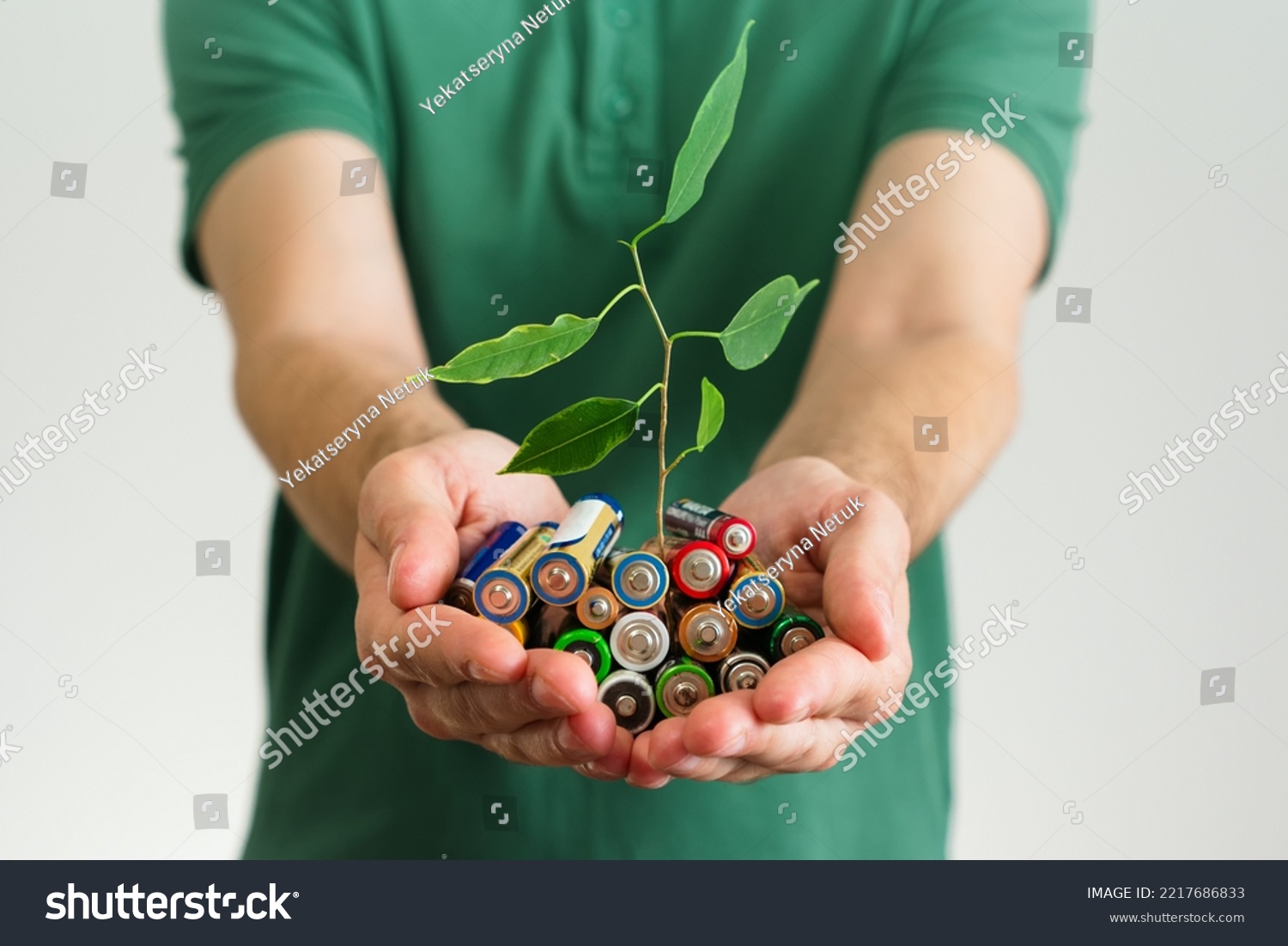 Leaf grows from a Alkaline batteries in hands. Green energy a symbol of clean energy resources. Concentration of waste recycling and environmental pollution #2217686833