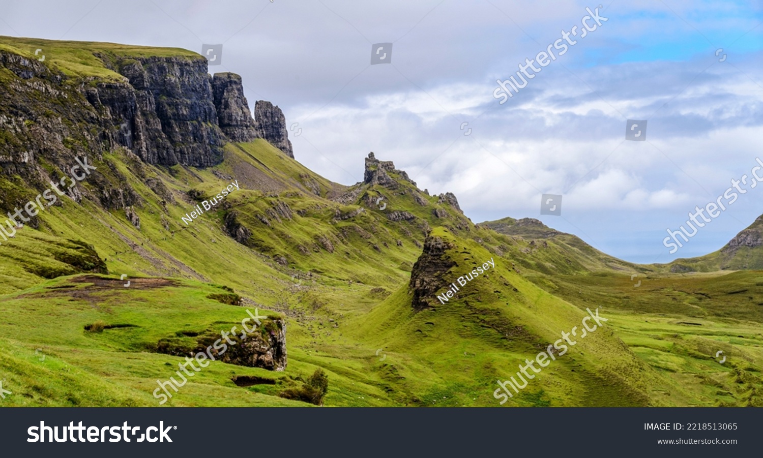Beautiful,dramatic Scottish mountainous scenery,pointed,jagged mountain peaks and sheer cliff faces, along the Quiraing hills walk,green grass and shrub covered in the mid summer,north eastern Skye. #2218513065