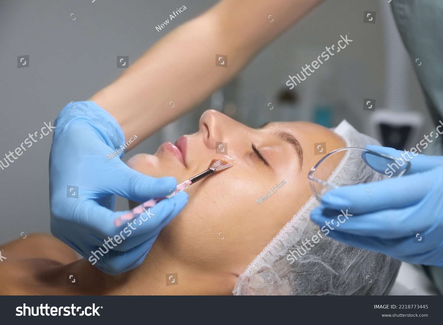 Cosmetologist applying chemical peel product on client's face in salon #2218773445