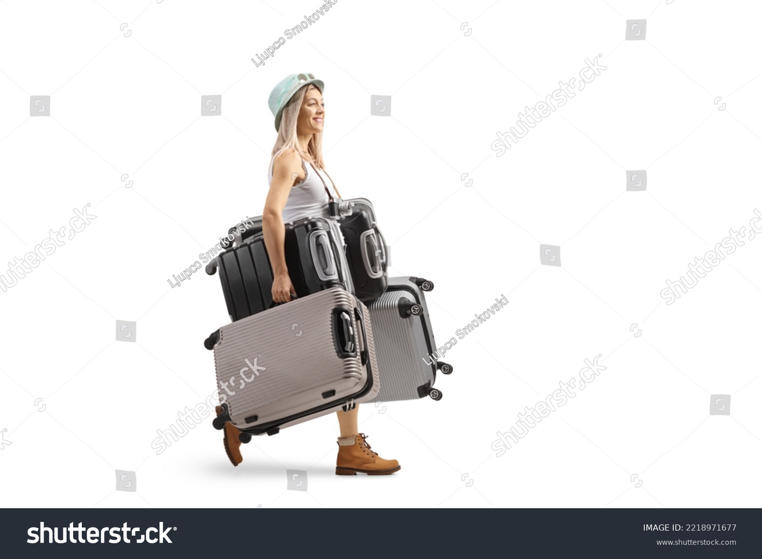 Full length profile shot of a young woman walking and carrying many suitcases isolated on white background #2218971677