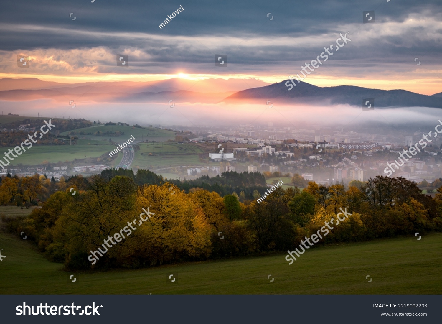 Foggy fall morning near Banska Bystrica. Landscape with forests and mountains around the city. Autumn colored trees at sunrise. #2219092203