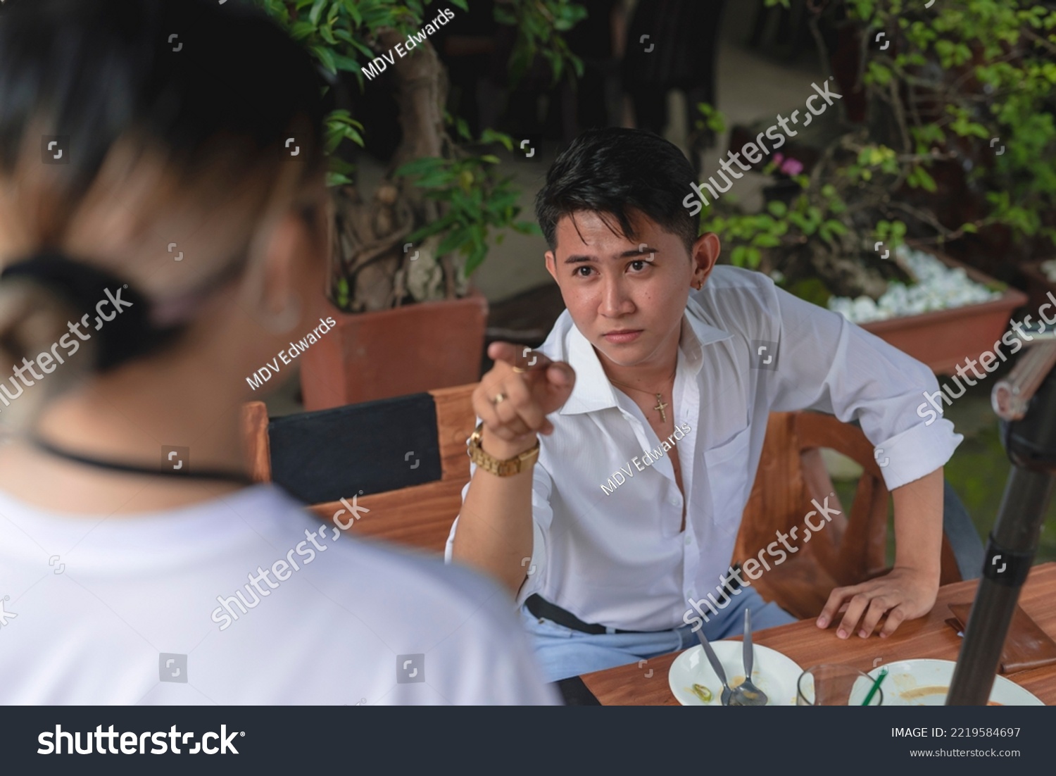 An arrogant young man complains about poor service or terrible food to a waitress. A rude and condescending customer belittling and criticizing the restaurant staff. #2219584697