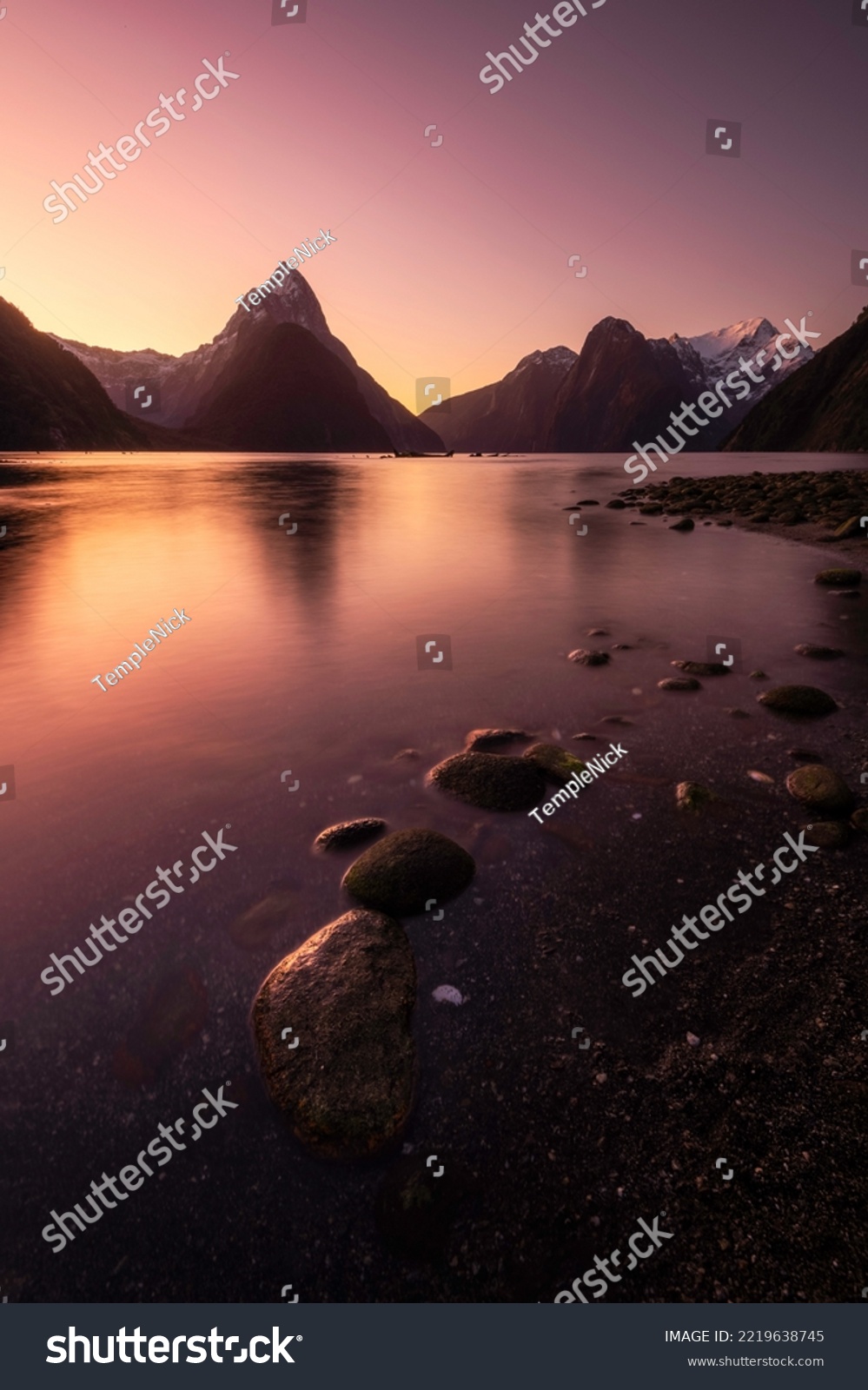 Intense twilight colors glow in the clear morning sky over the Milford Sound of New Zealand in the Fiordland National Park. #2219638745