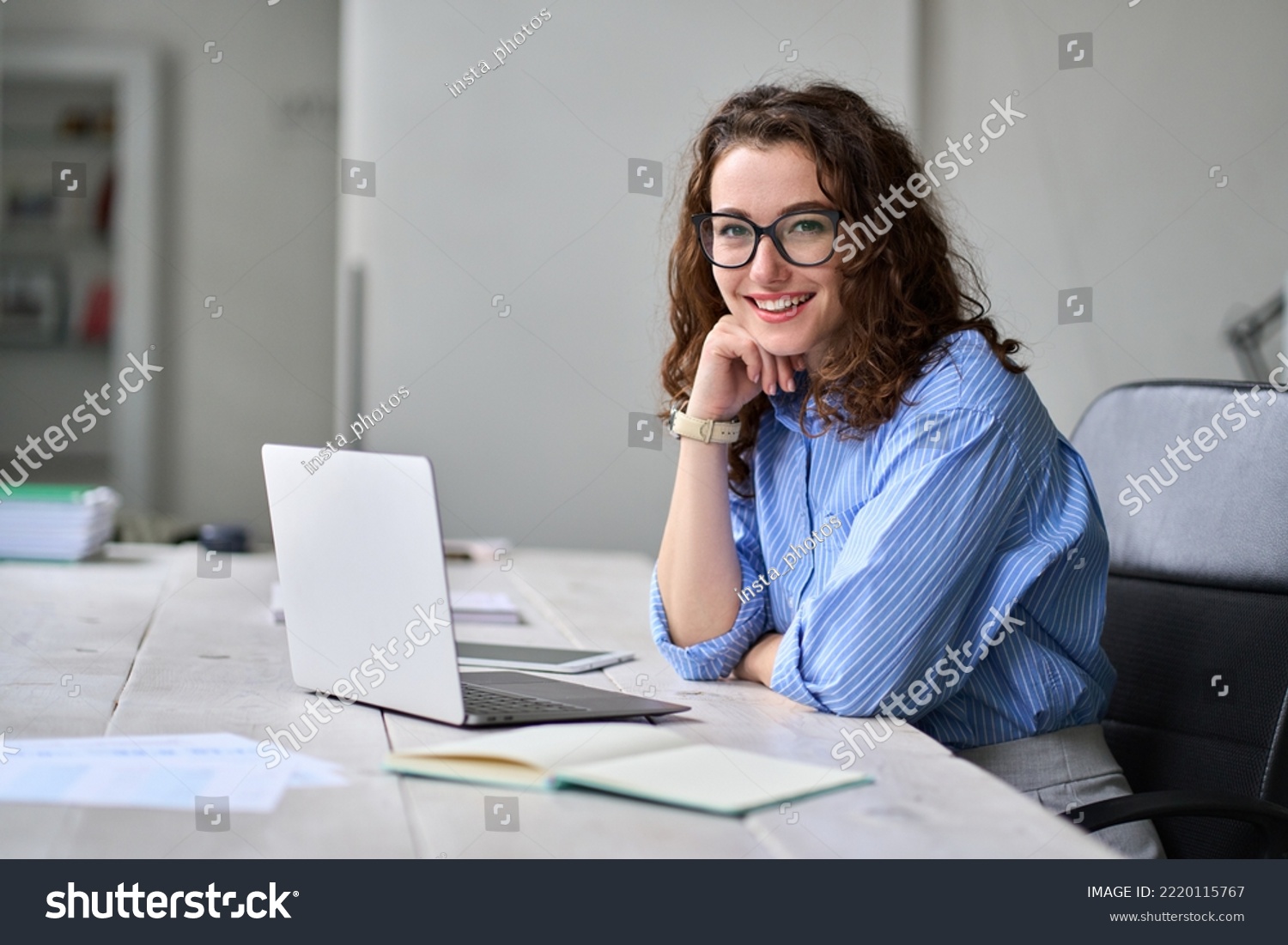 Young happy business woman company employee sitting at desk working on laptop. Smiling female professional entrepreneur worker using computer in corporate modern office looking at camera. Portrait. #2220115767