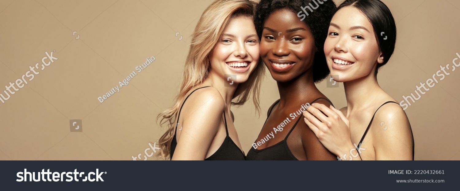 Multi-Ethnic Group of women with different types of skin together against a beige background. Diverse ethnicity women - Caucasian, African and Asian. #2220432661