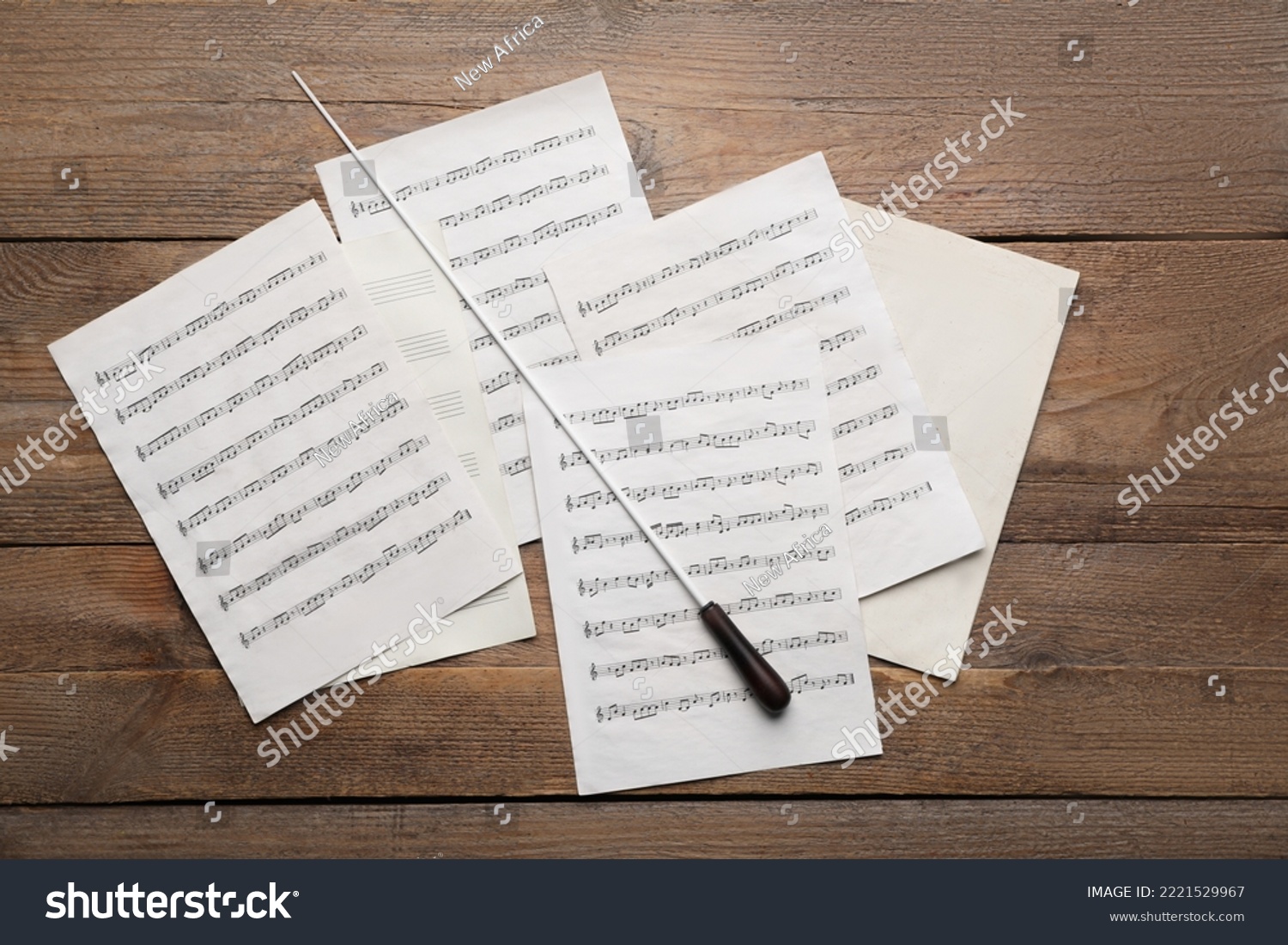 Conductor's baton and sheet music on wooden table, flat lay #2221529967