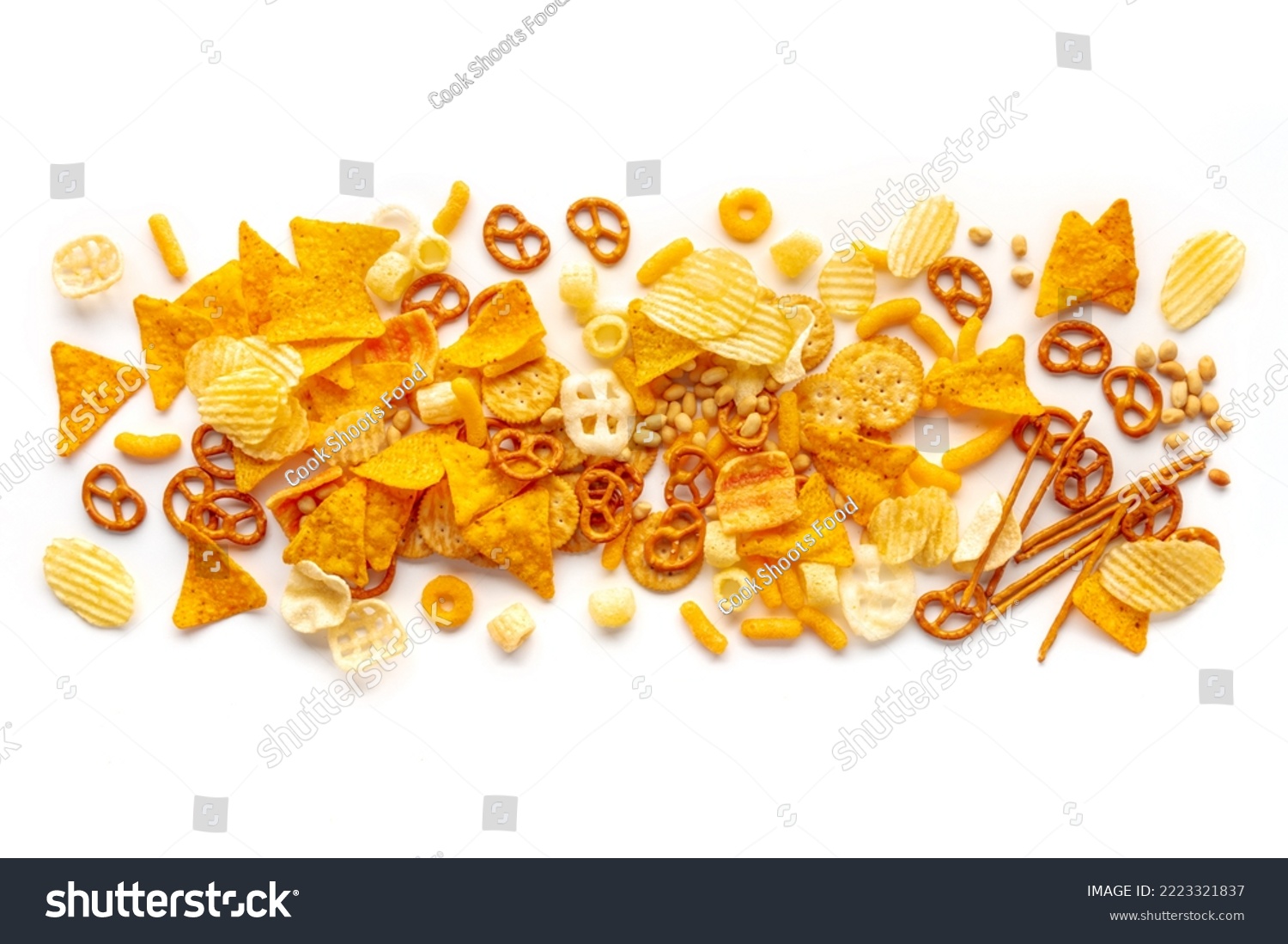 Salty snacks texture on a white background. Party food mix. Potato and tortilla chips, crackers and other appetizers, overhead flat lay shot #2223321837