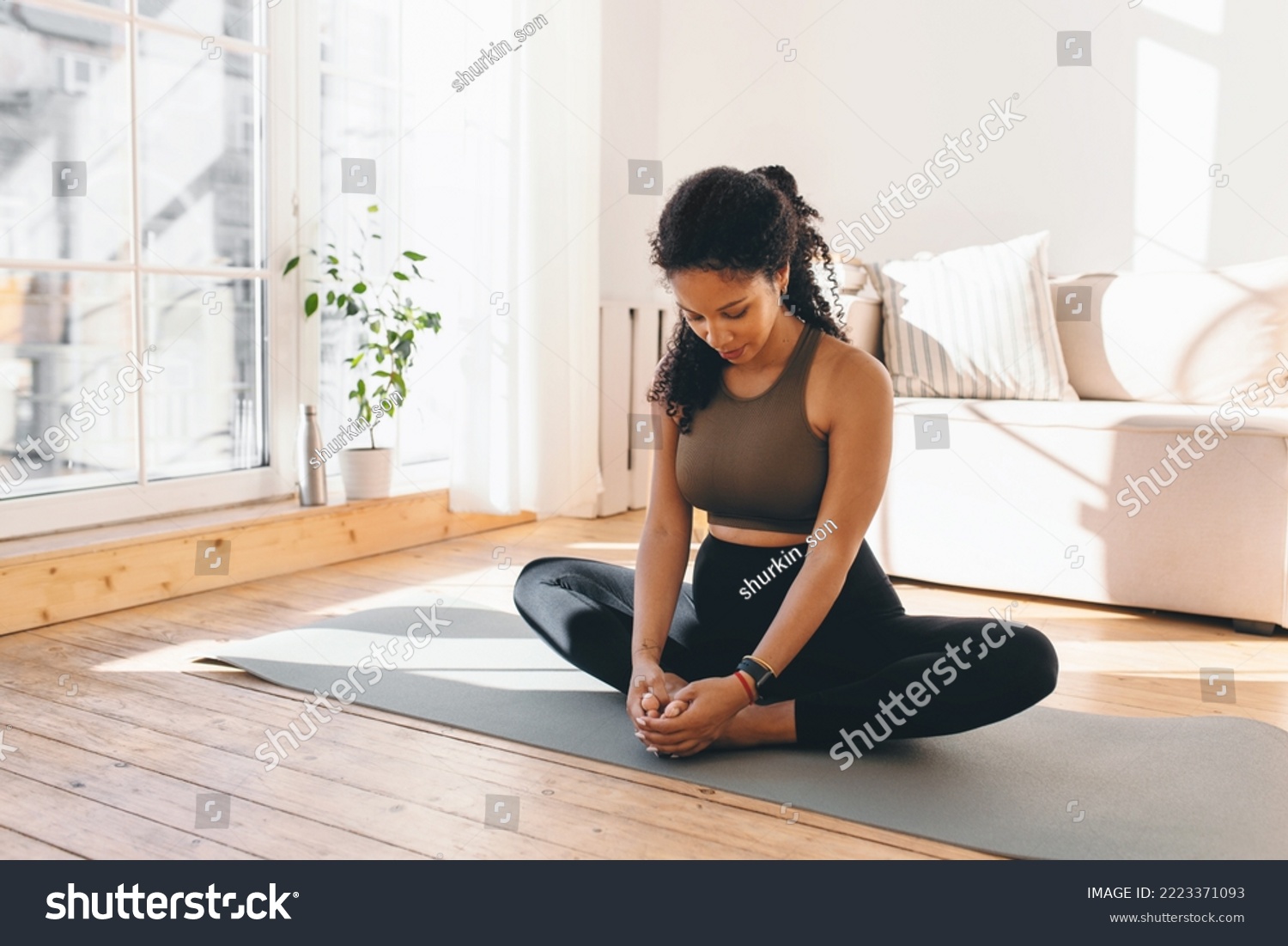 Active african american pregnant woman practicing yoga, sitting in butterfly or konasana pose, stretching muscles on mat, doing prenatal exercises for healthy pregnancy and prepare body for childbirth #2223371093