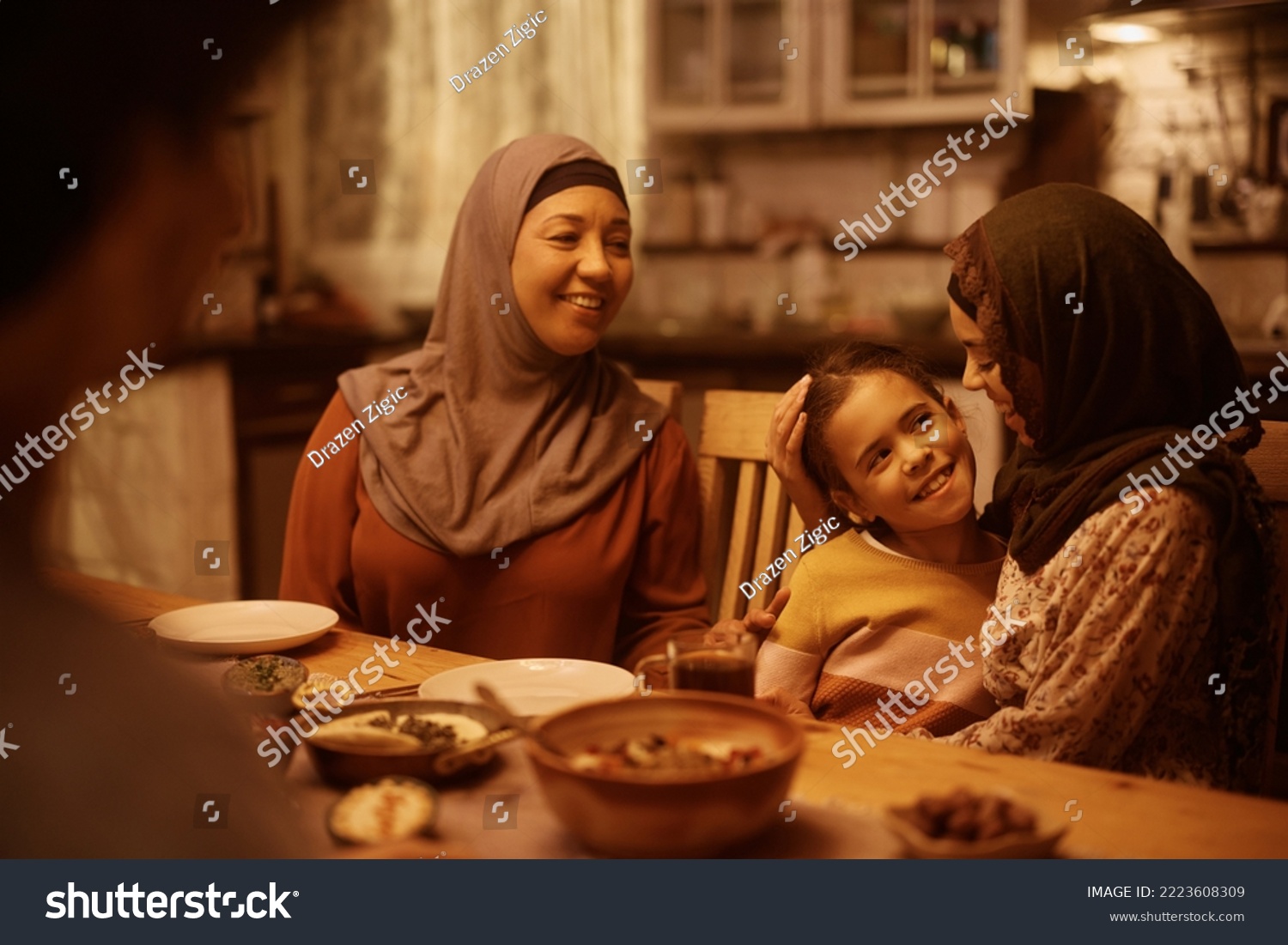 Happy Middle Eastern girl having dinner with extended family in dining room. #2223608309