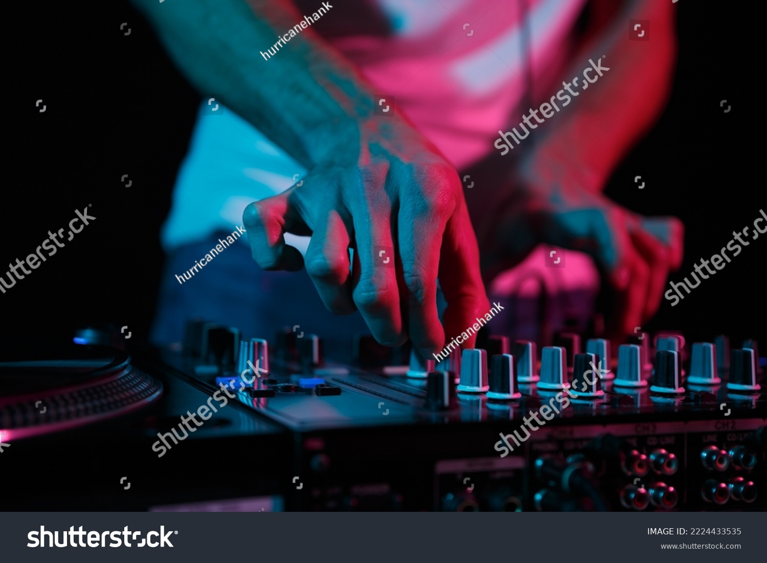 Disc jockey mixing techno music on rave party. Club dj playing set on stage. Disk jokey adjusting volume frequency regulator on sound mixer  #2224433535
