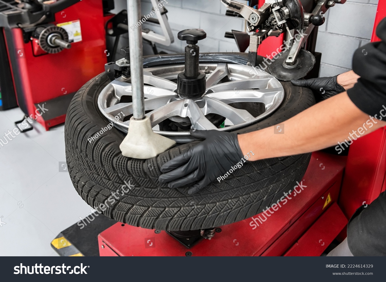 From above crop male worker of garage in gloves dismantling tire from rim using special machinery #2224614329