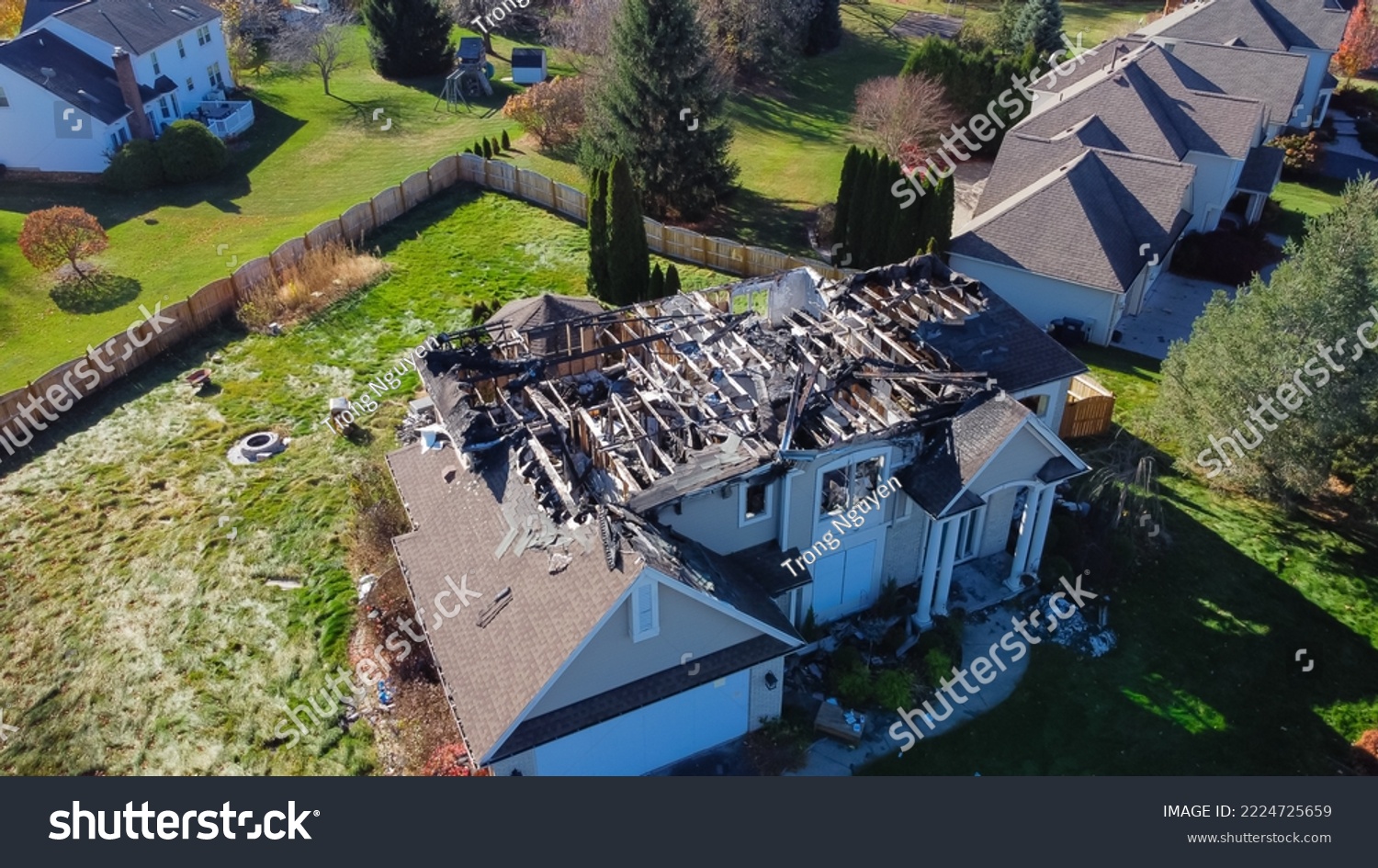 Aerial view upscale residential neighborhood with burnt house between other two story homes in Rochester, New York. Property totally damaged by fire disaster, insurance claim background #2224725659