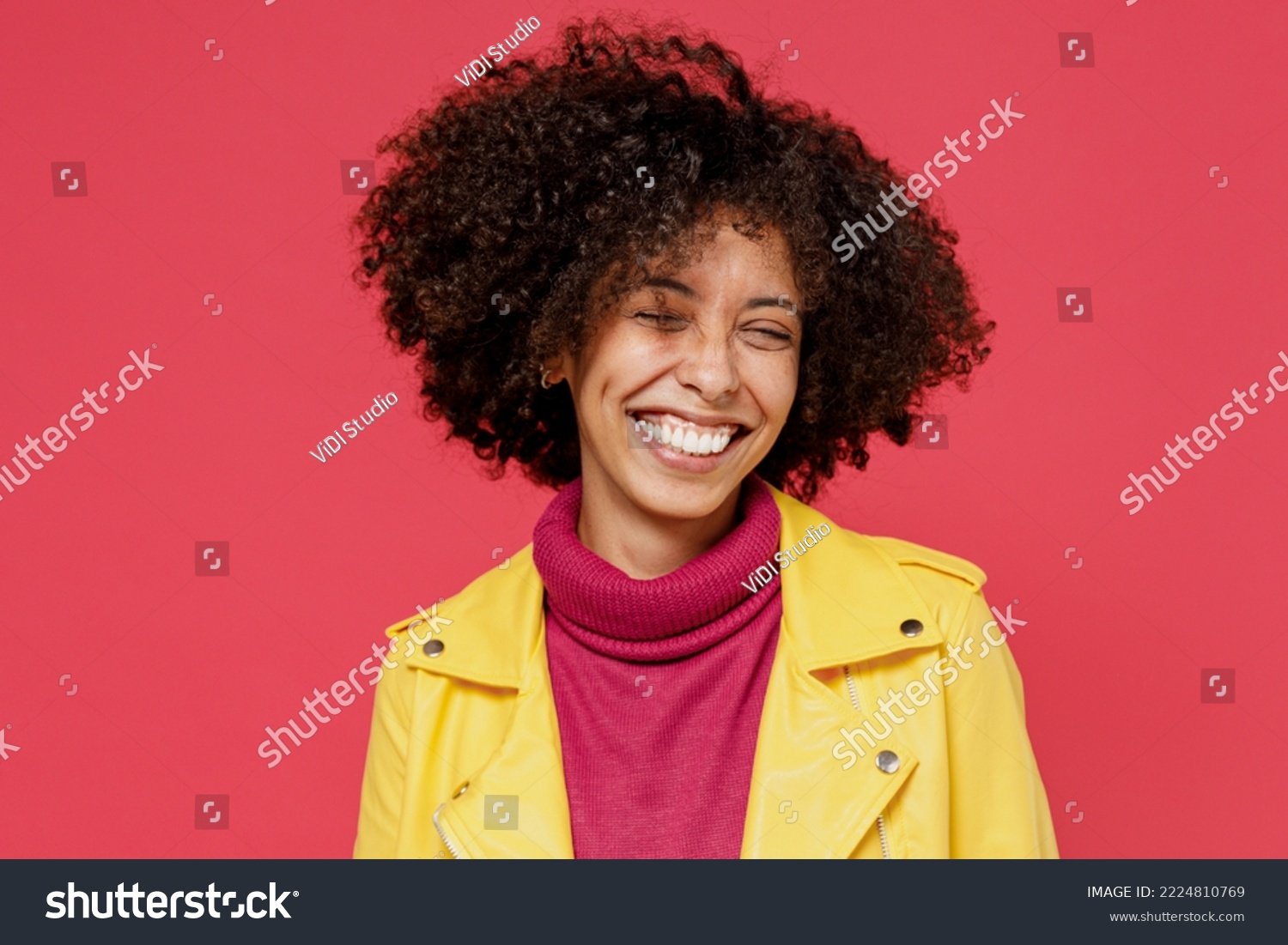 Laughing bright happy fun young curly black latin woman 20s years old wears yellow jacket keep eyes closed smiling isolated on plain red background studio portrait. People emotions lifestyle concept #2224810769