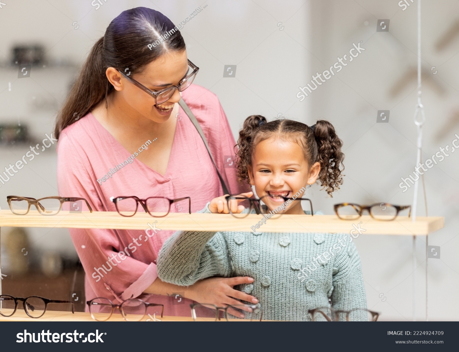 Decision, glasses and girl with her mother at the optometrist for vision and check on eyes together. Customer, medical and child shopping for eyeglasses with her mom at the ophthalmologist clinic #2224924709