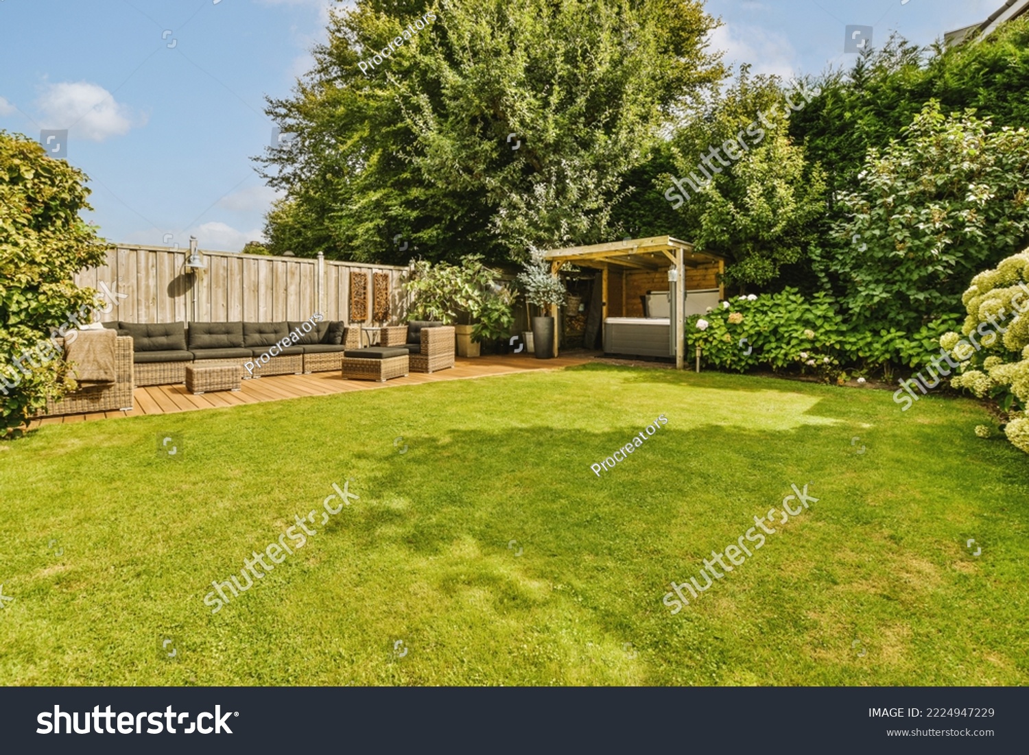 Neat paved patio with sitting area and small garden near wooden fence #2224947229