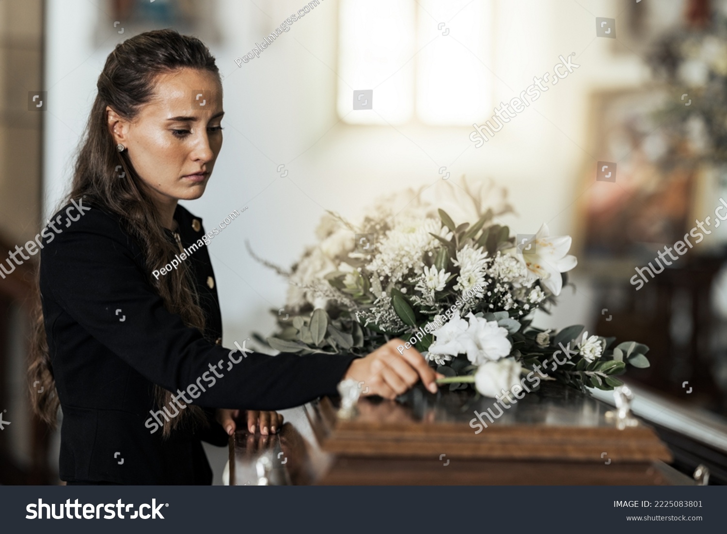 Funeral, sad and woman with flower on coffin after loss of a loved one, family or friend. Grief, death and young female putting a rose on casket in church with sadness, depression and mourning #2225083801