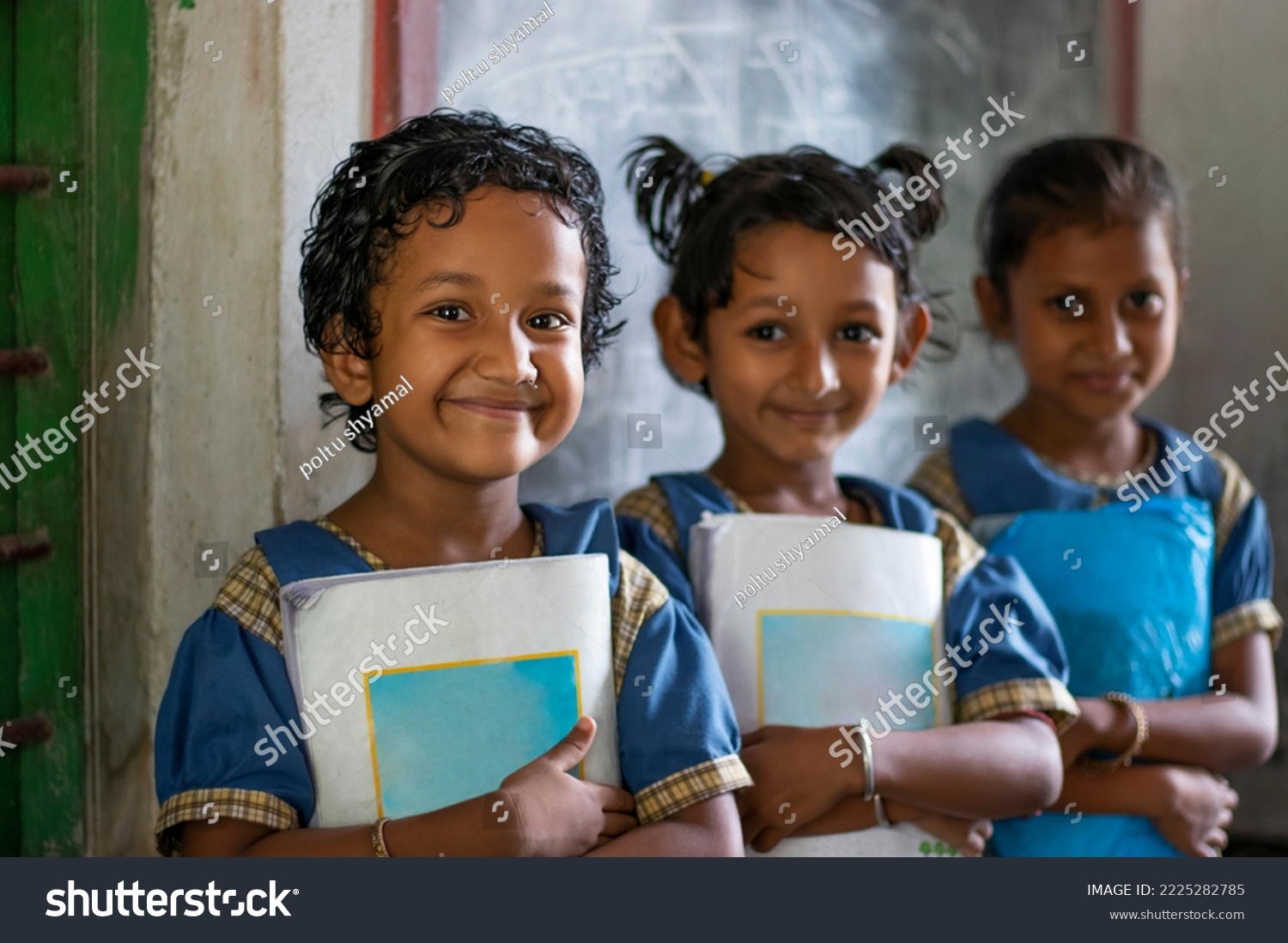 Three School Children's holding books standing at school #2225282785