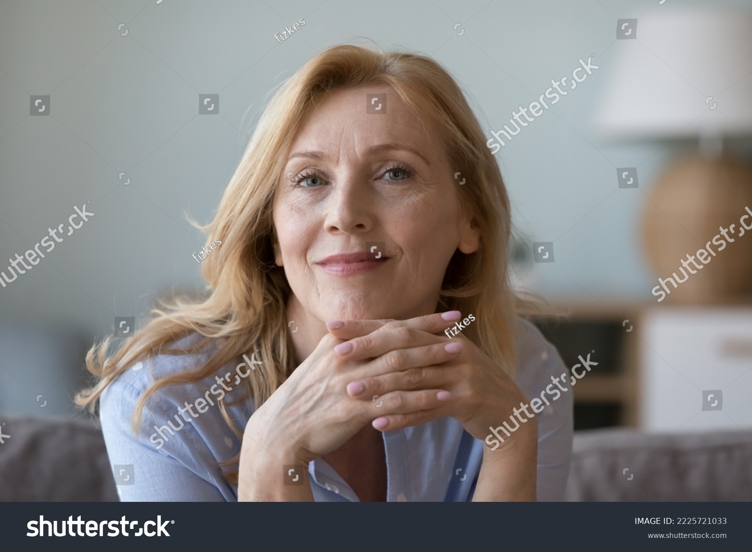 Head shot close up portrait attractive middle-aged woman resting on cozy sofa alone at home staring at camera, posing for photo looks peaceful and confident. Midlife, medical insurance cover for older #2225721033