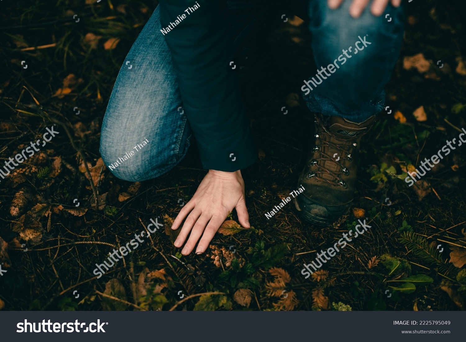 The girl touches the ground with her palm in the autumn forest. Forest bathing. Communication with the earth. Close-up #2225795049