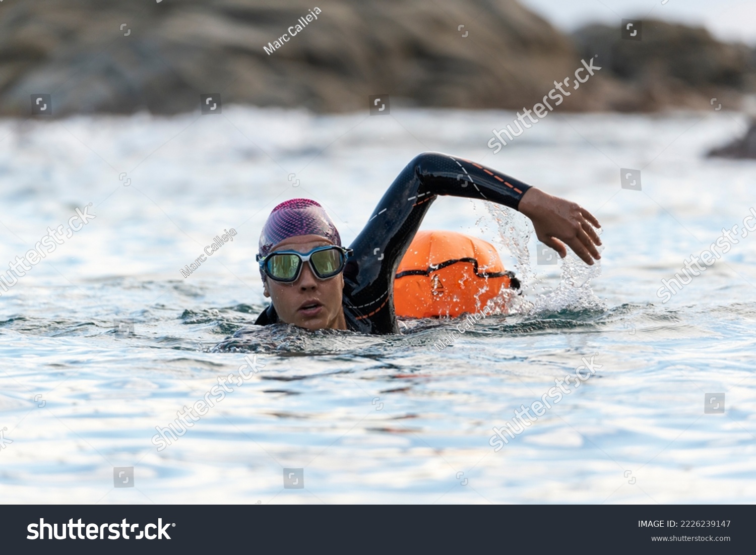 Woman swimming in open water with wetsuit and buoy #2226239147