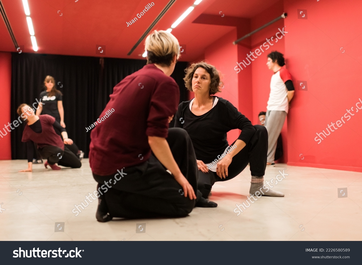 Two young women on their knees look at each other's faces with a sad expression, in a show of body theater #2226580589