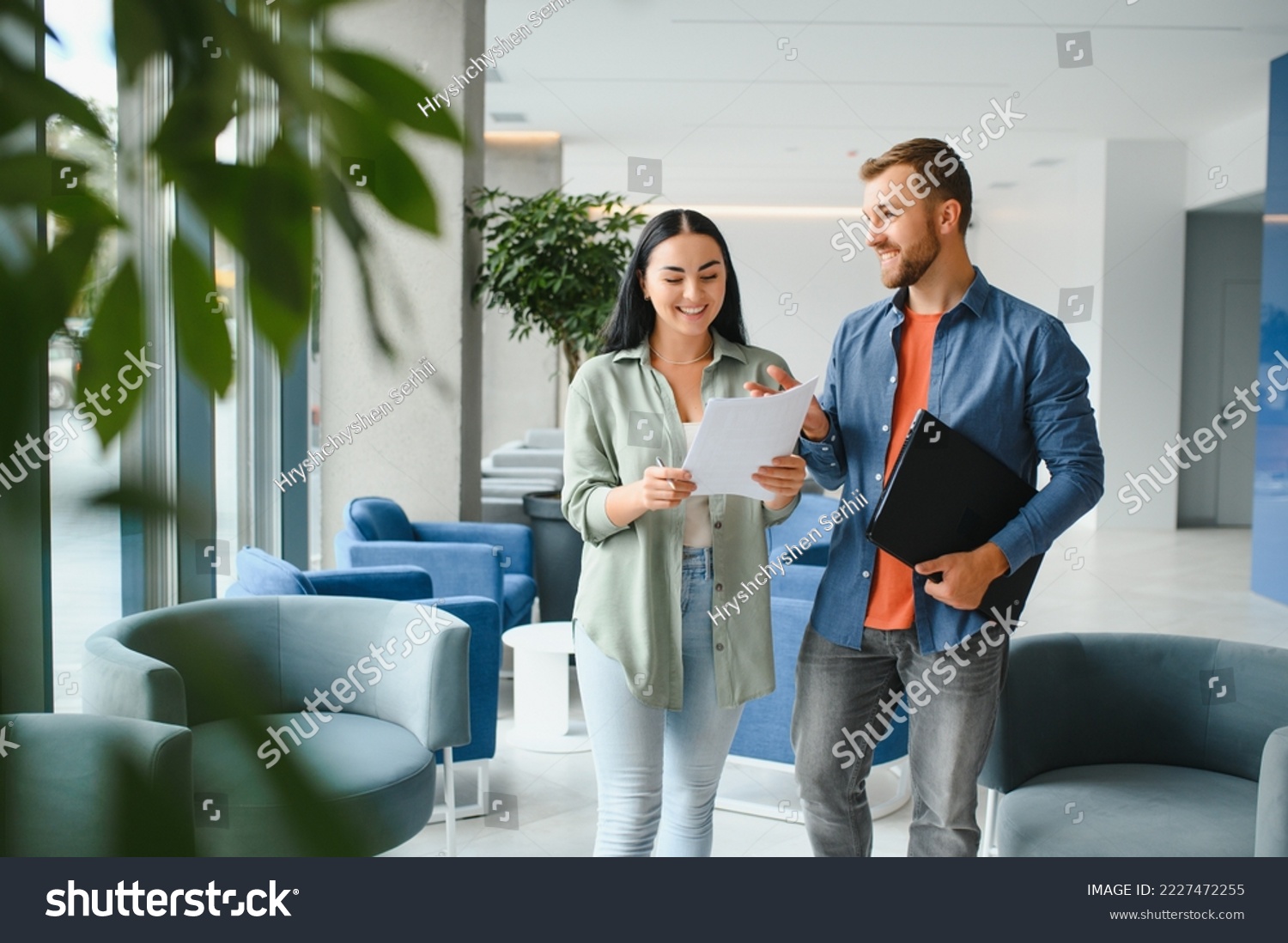 Two business coworkers walking through a lobby of an office building. #2227472255