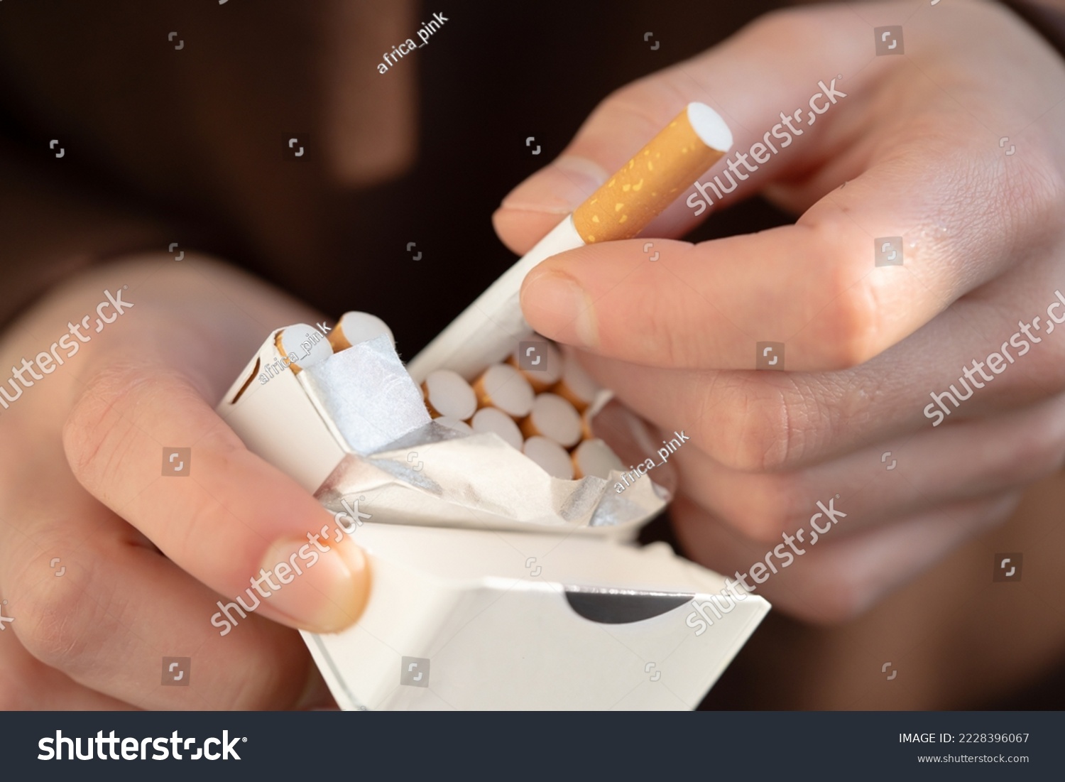 A man holds a pack of cigarettes in his hands, hand with a cigarette closeup. Person with a bad habit that is unhealthy #2228396067